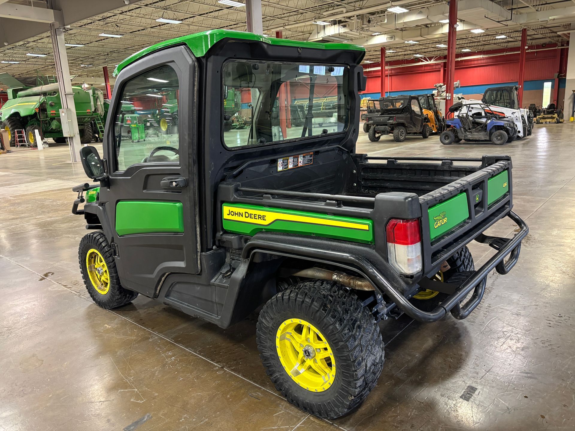 Green and yellow John Deere Gator utility vehicle with a cab and open cargo bed.