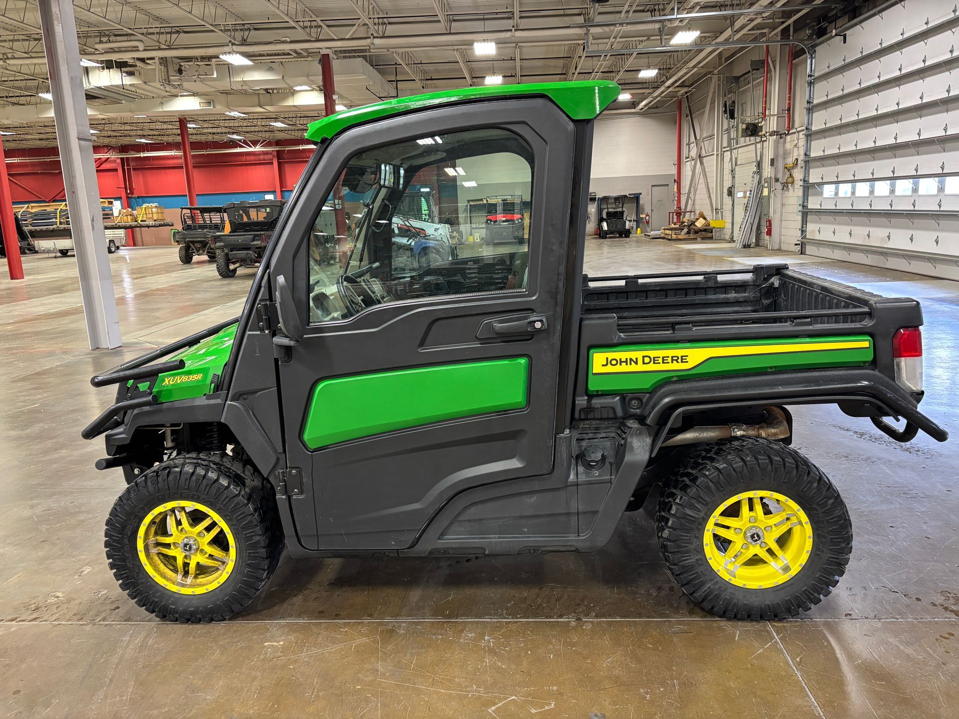 John Deere Gator utility vehicle, black and green, parked indoors.