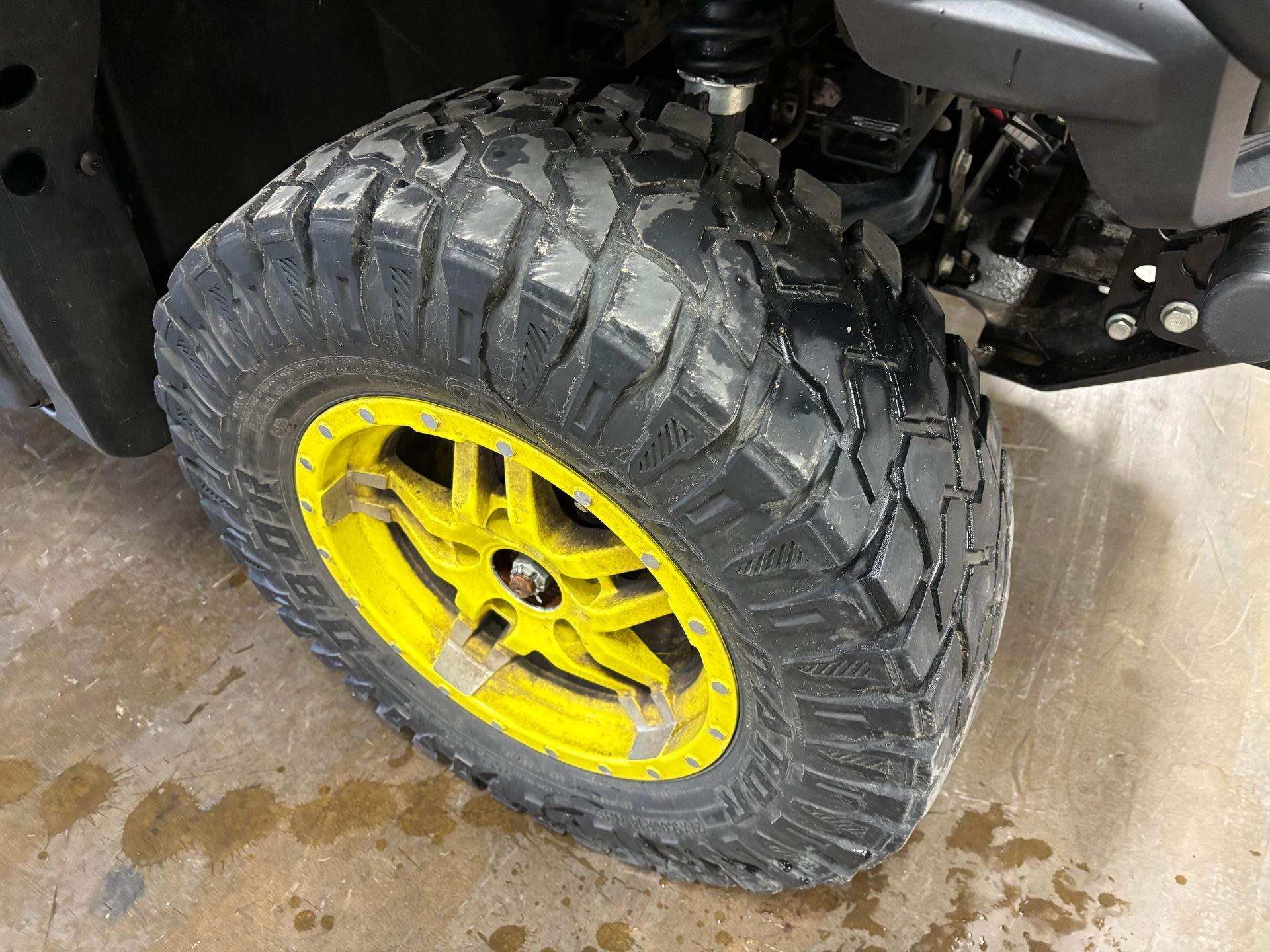 Yellow rimmed tire on a vehicle, showing rugged tread on a gray surface.