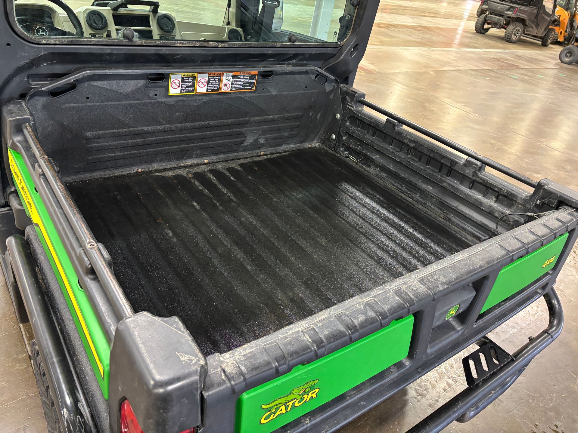 Empty black bed of a John Deere Gator utility vehicle, with green accents.