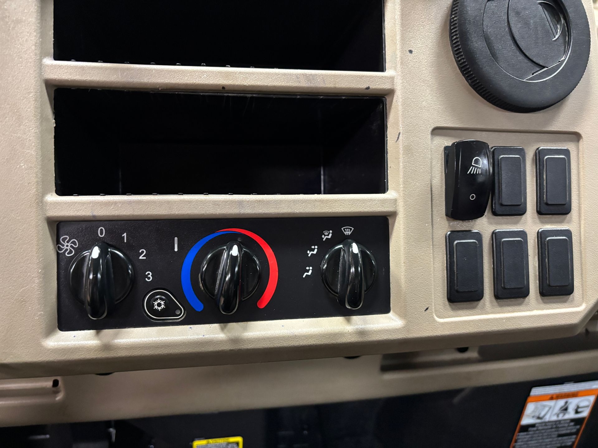 Dashboard with fan controls, air conditioning, and switches, in tan.