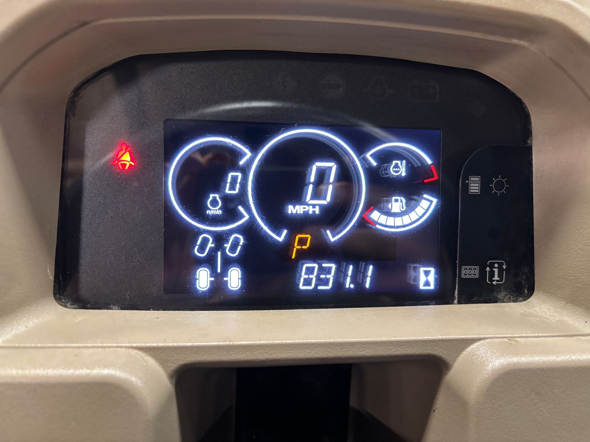 Dashboard display: speedometer at 0 MPH, fuel gauge low, parking brake light on, odometer reading 831.1.
