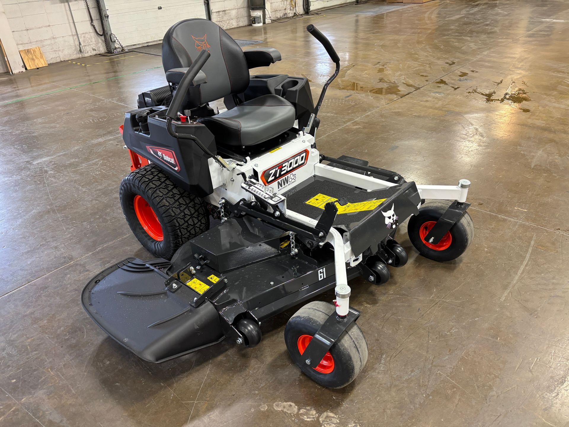 Black and white Bobcat zero-turn lawnmower with red accents; parked on a concrete floor.