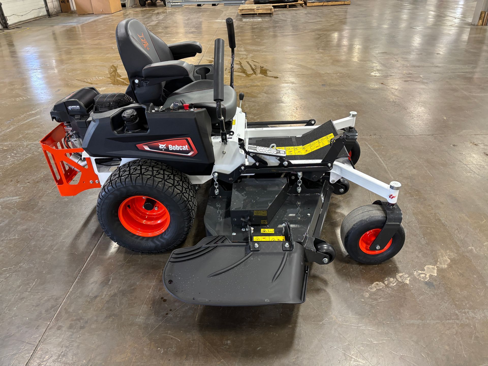 Zero-turn lawnmower with a black and red frame, on a concrete floor.
