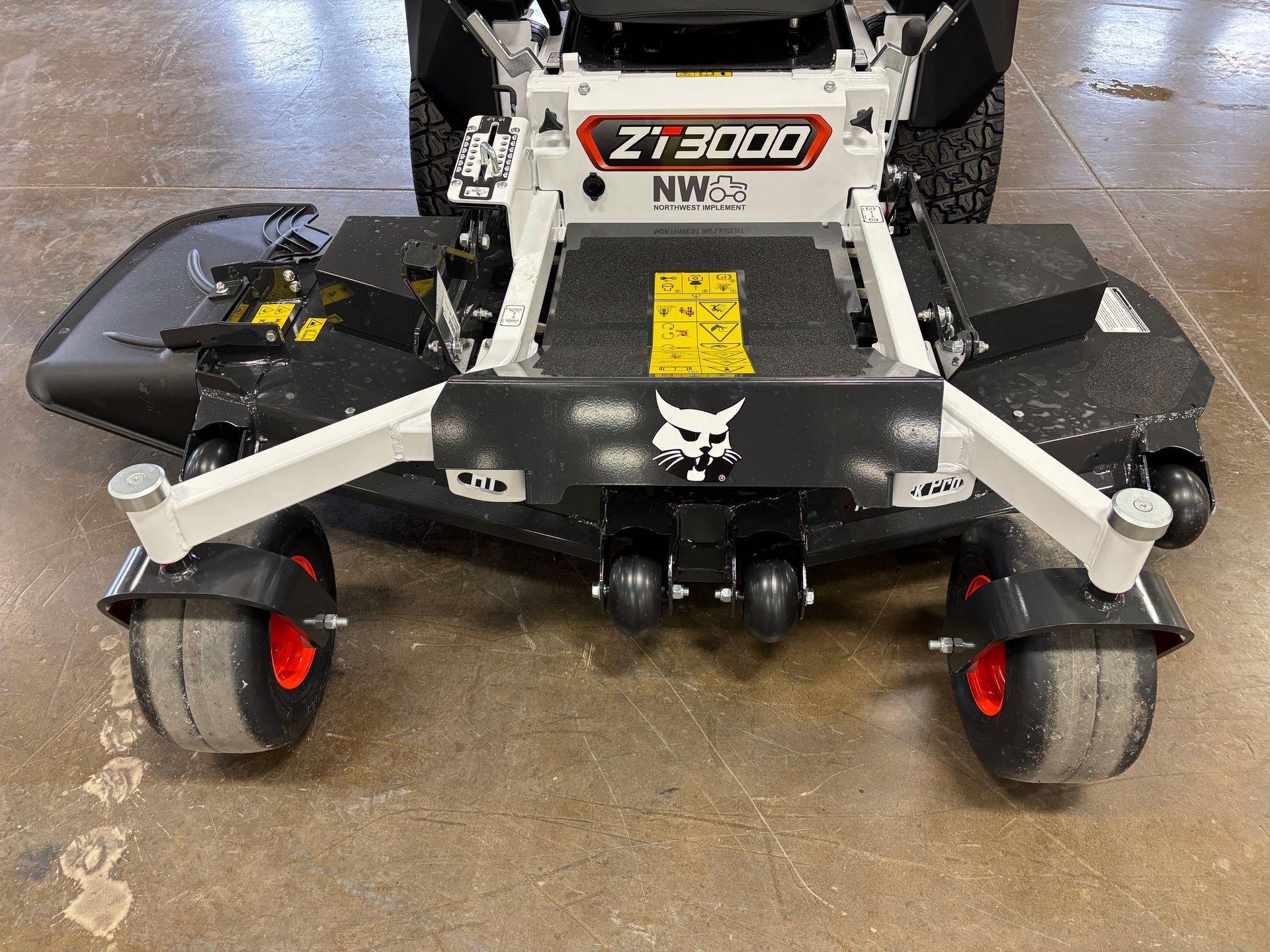 Front view of a white and black Bobcat ZT3000 zero-turn mower with large tires on a concrete floor.