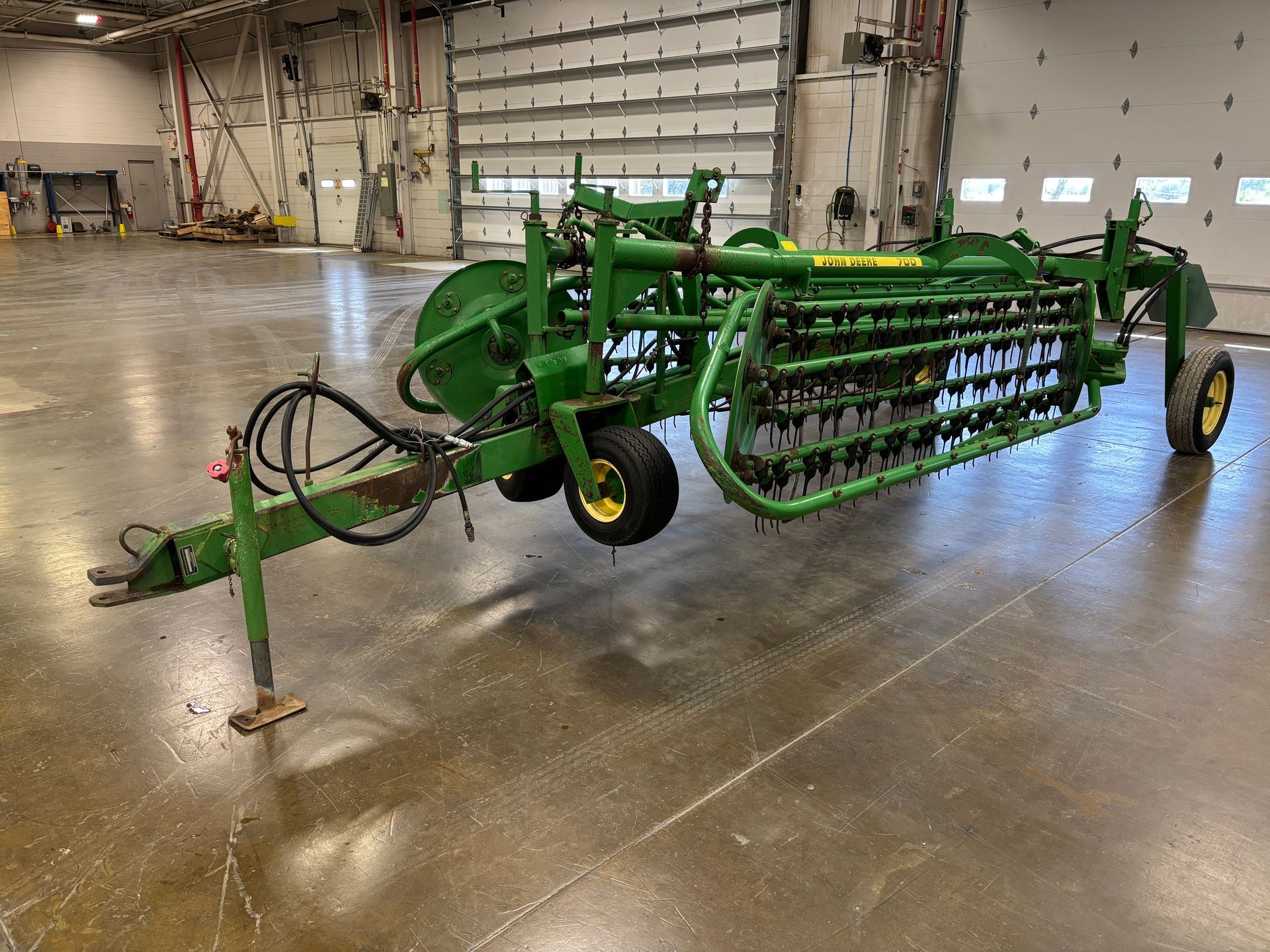 Green John Deere hay rake in a warehouse.