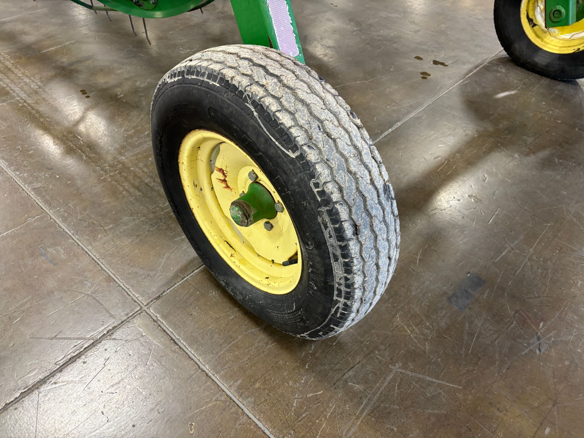John Deere tractor wheel with yellow rim and worn black tire.