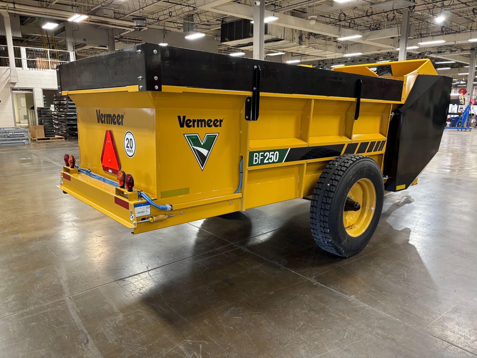 Yellow Vermeer manure spreader trailer on a gray floor.