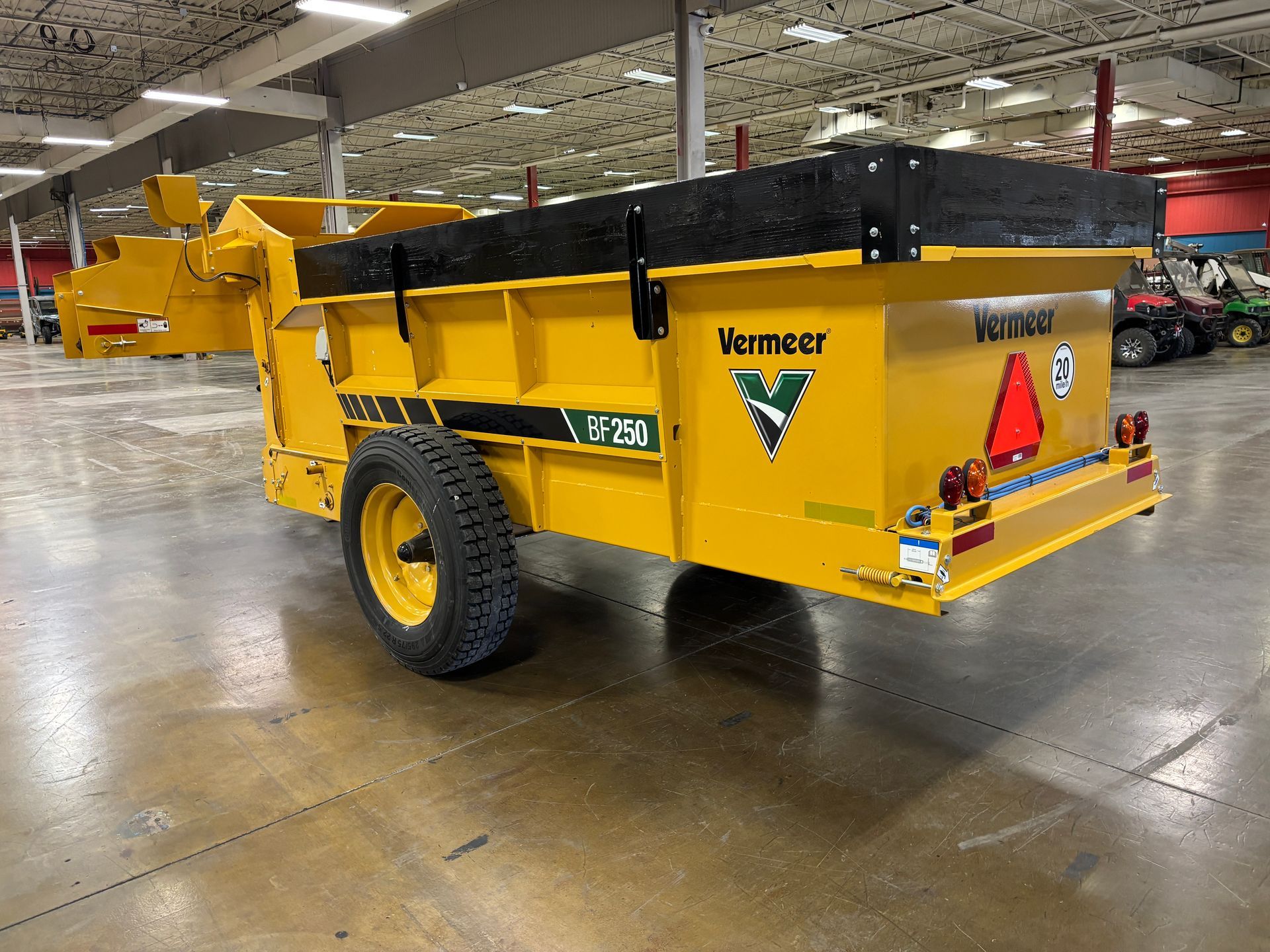 Yellow Vermeer VPM50 compost spreader trailer with a black top, indoors.