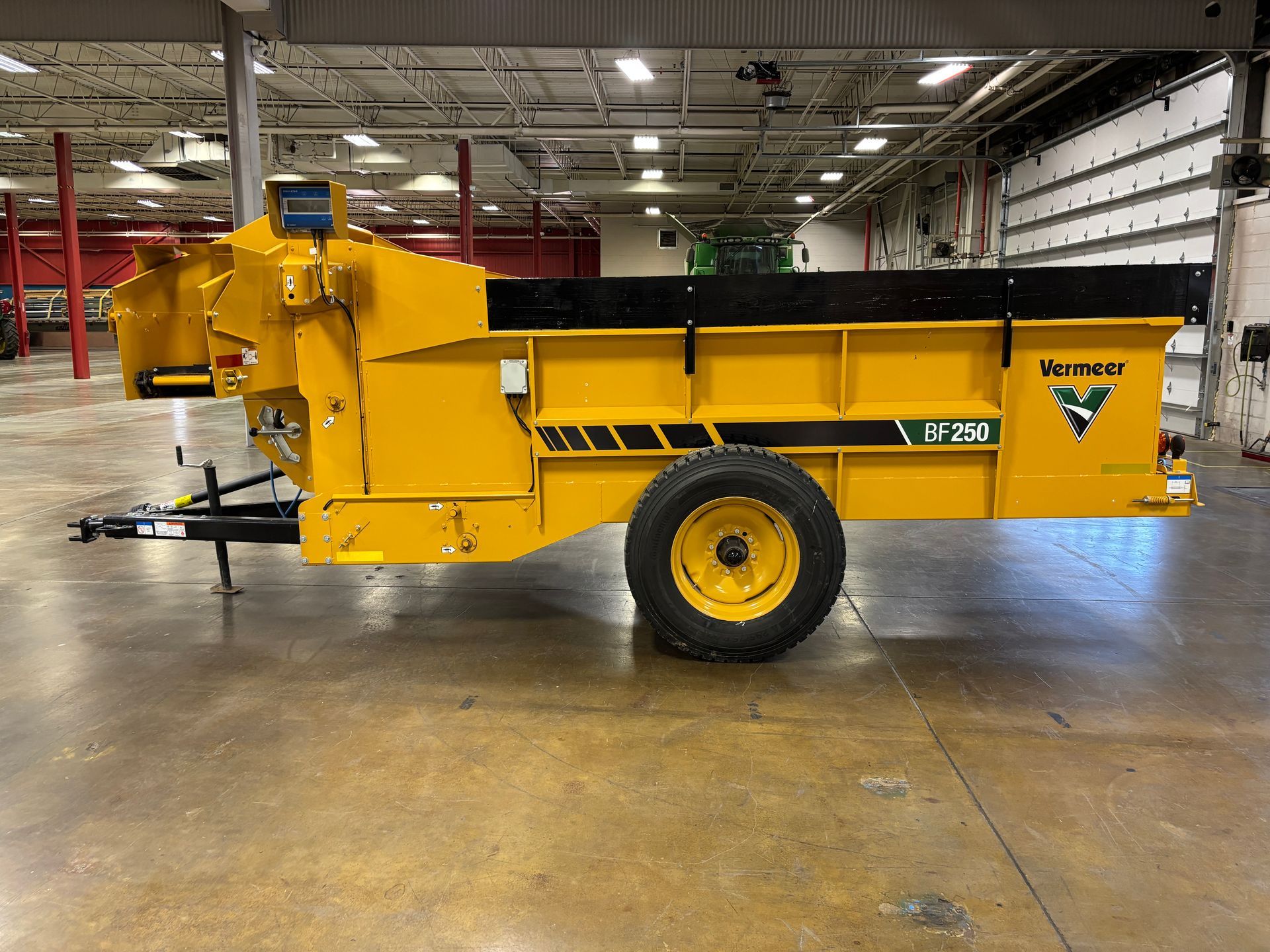 Yellow manure spreader trailer, indoors, with a black top.