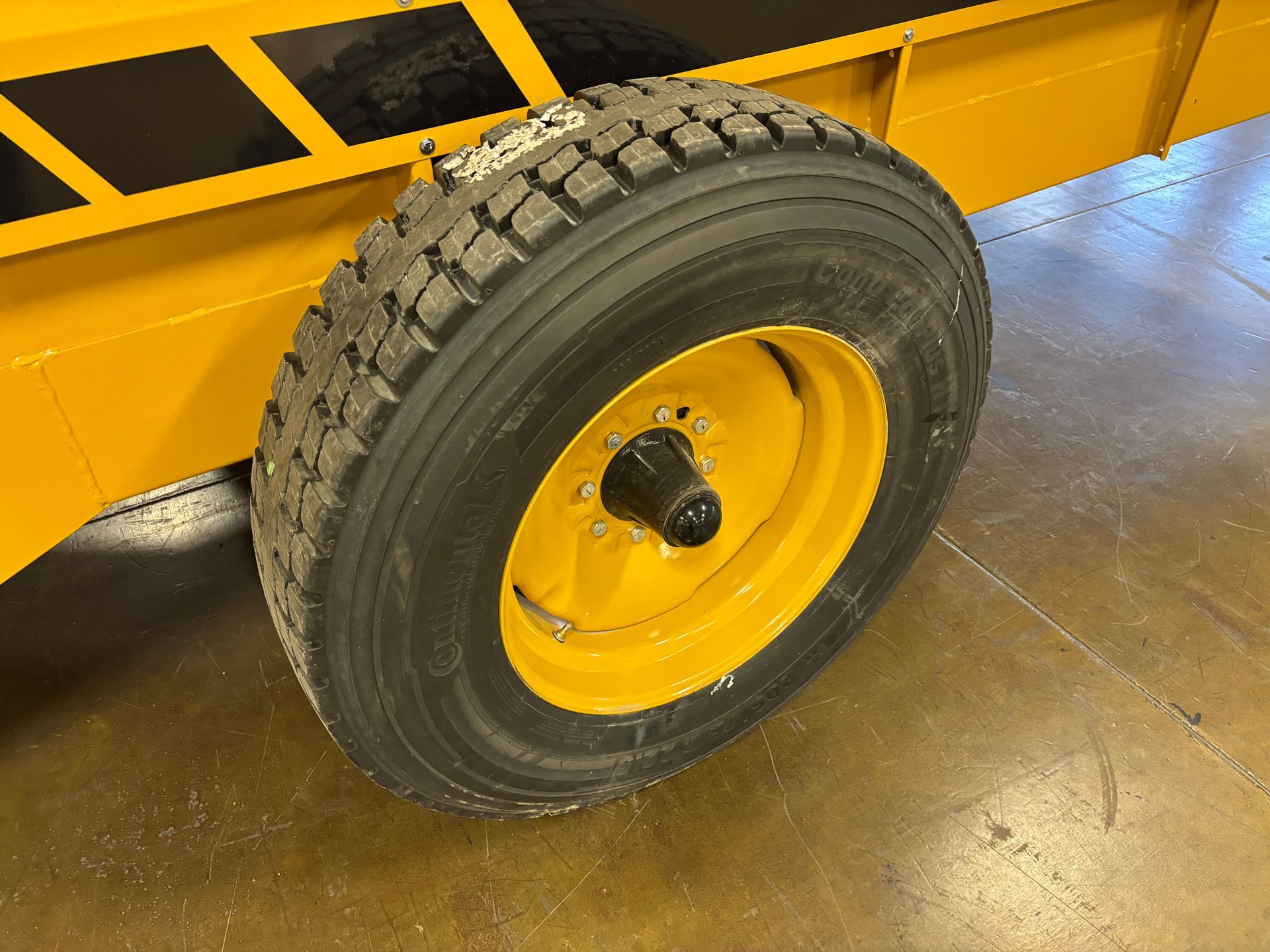 Yellow trailer wheel on yellow trailer, tire has tread.
