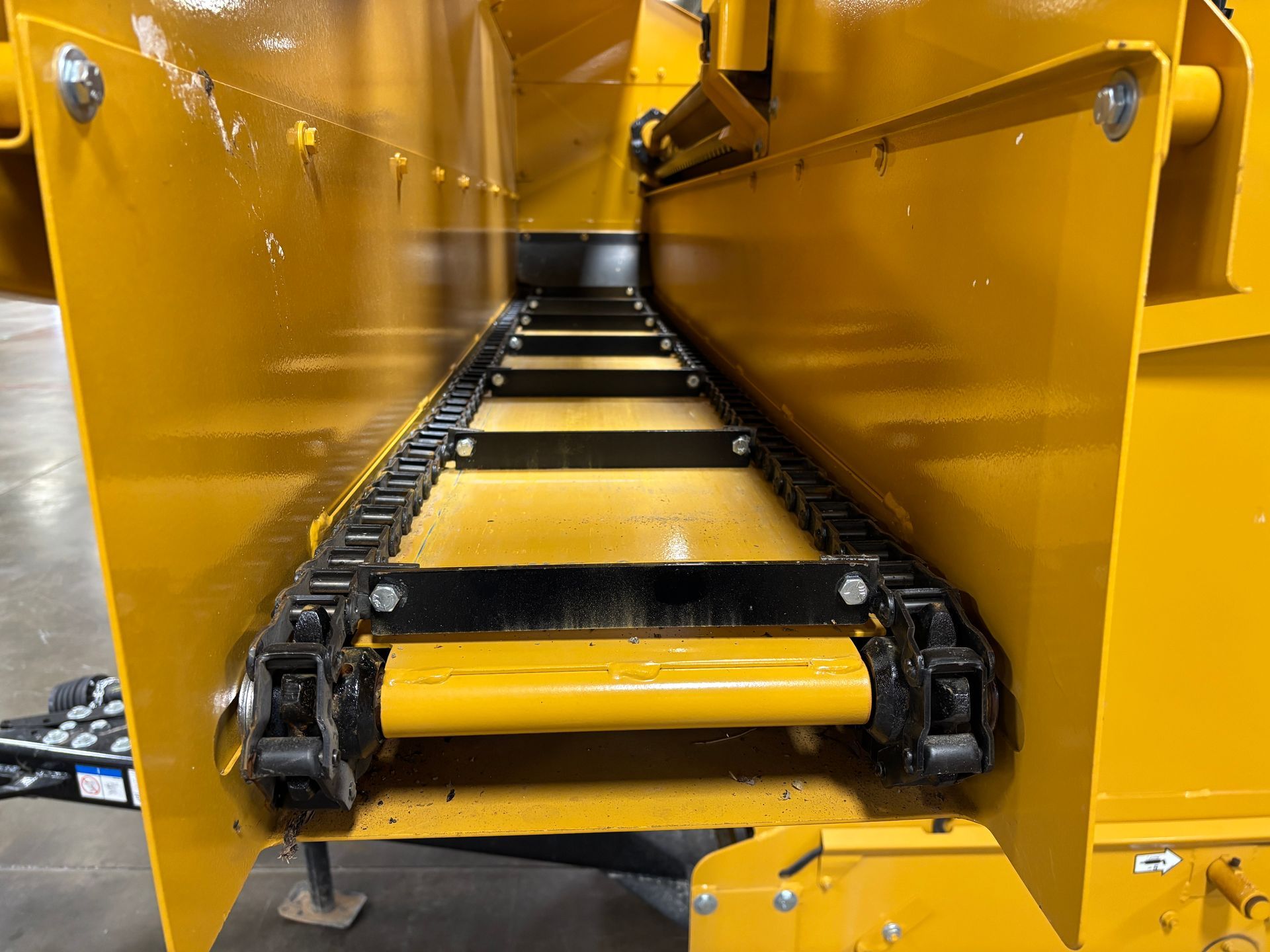 Yellow metal conveyor belt, viewed from its interior, with black chain links and yellow frame.
