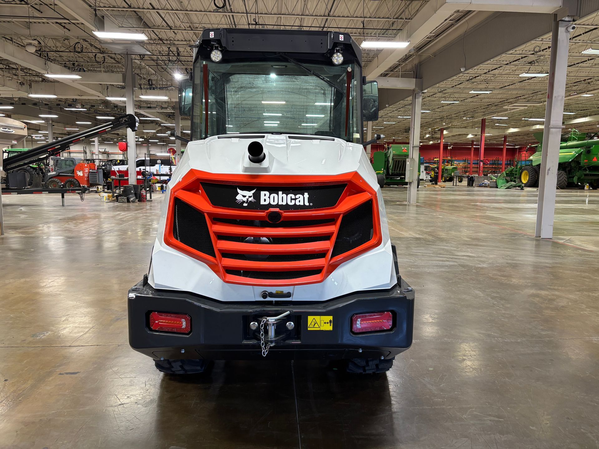 Rear view of a white and orange Bobcat skid-steer loader in a warehouse.
