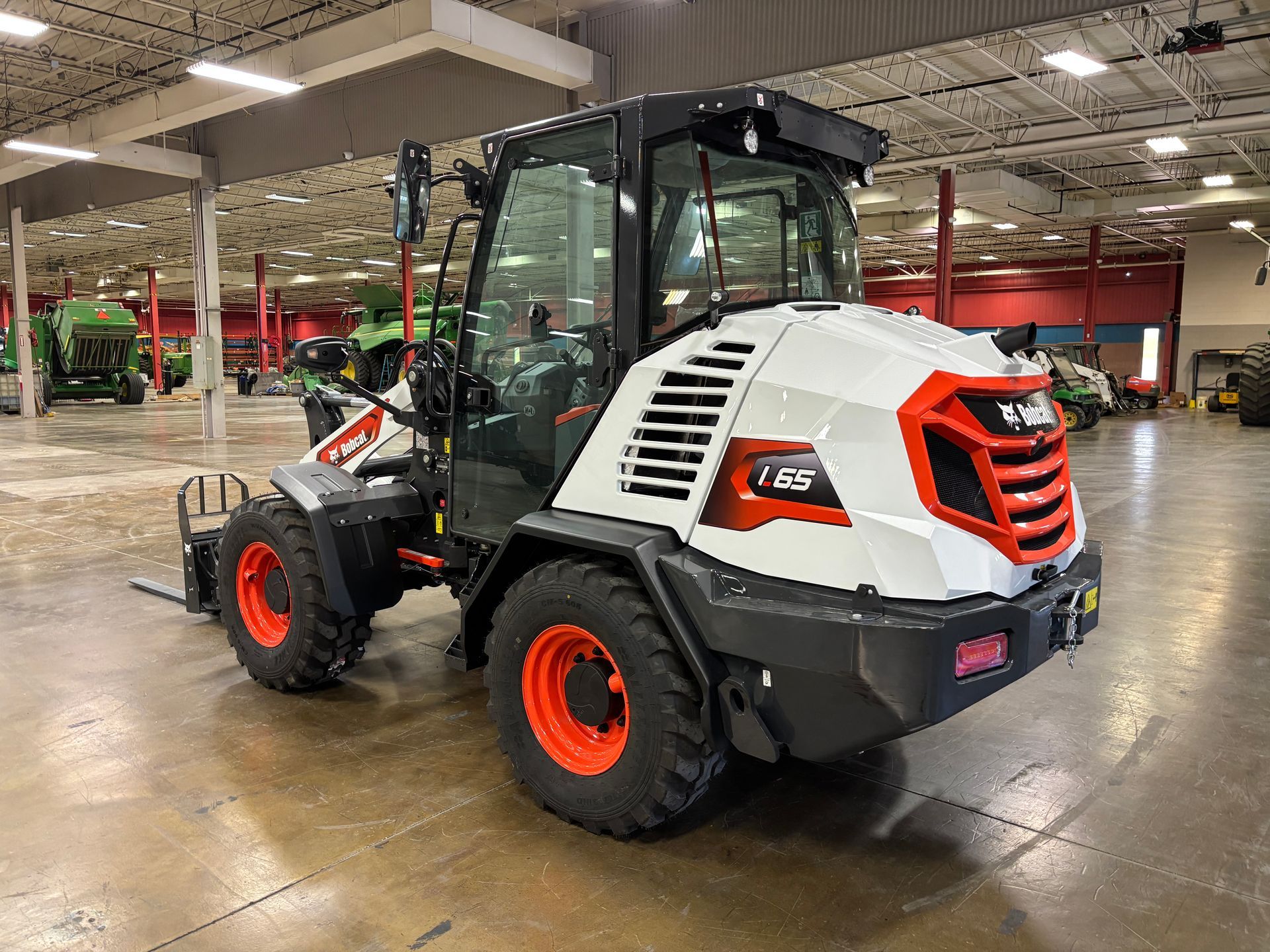 White and orange Bobcat L25 front-end loader inside a building, with large tires.