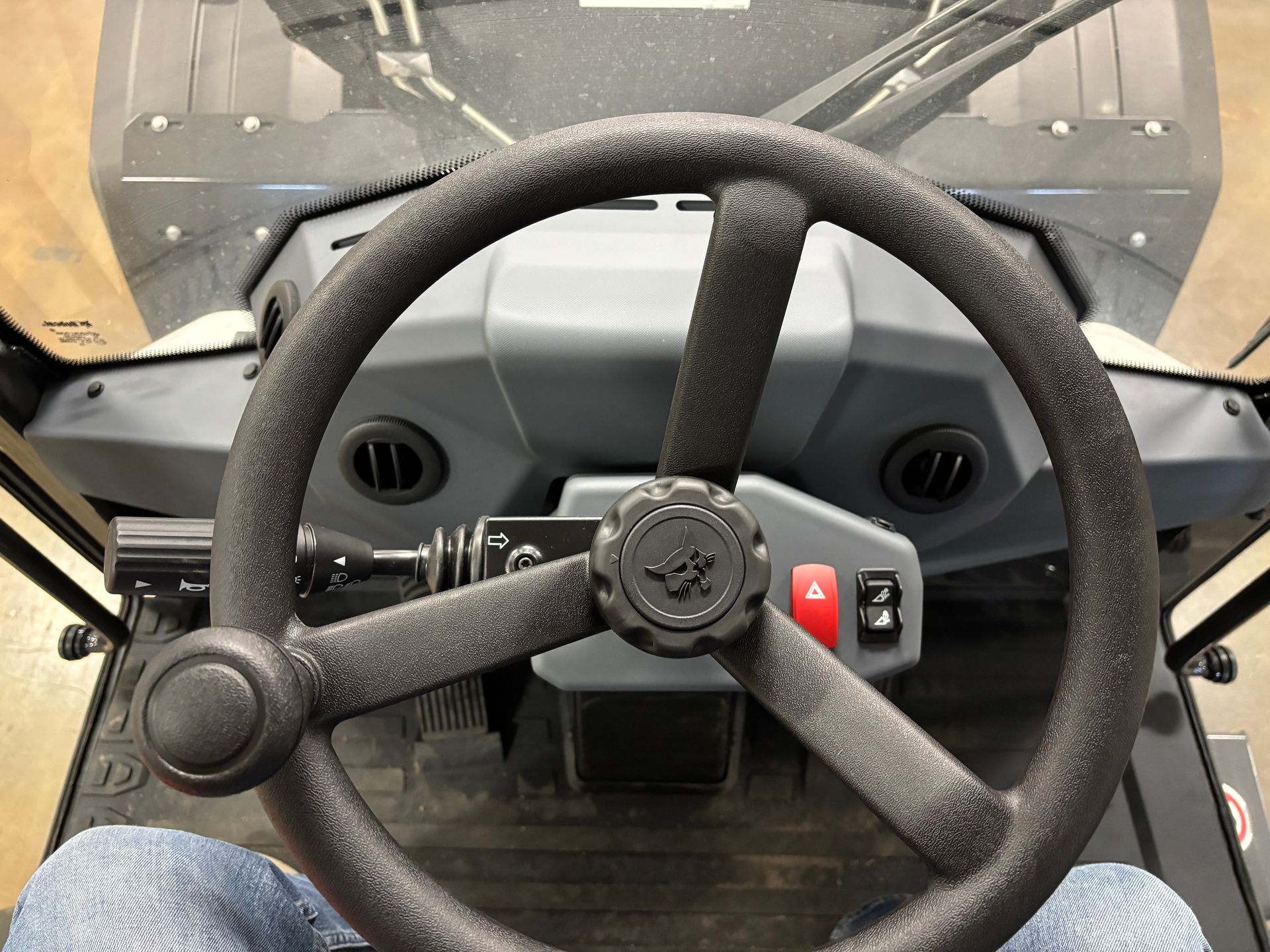 Steering wheel of a tractor with a black, textured rim; dashboard visible.
