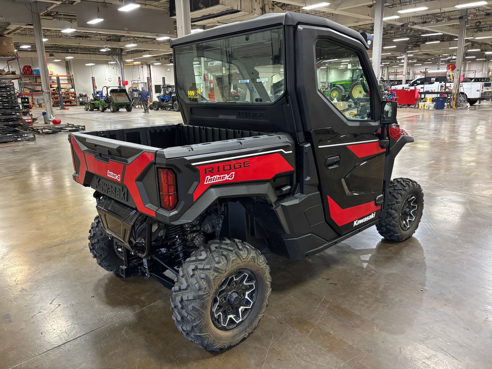 Black and red UTV with a cab and a truck bed, parked indoors.