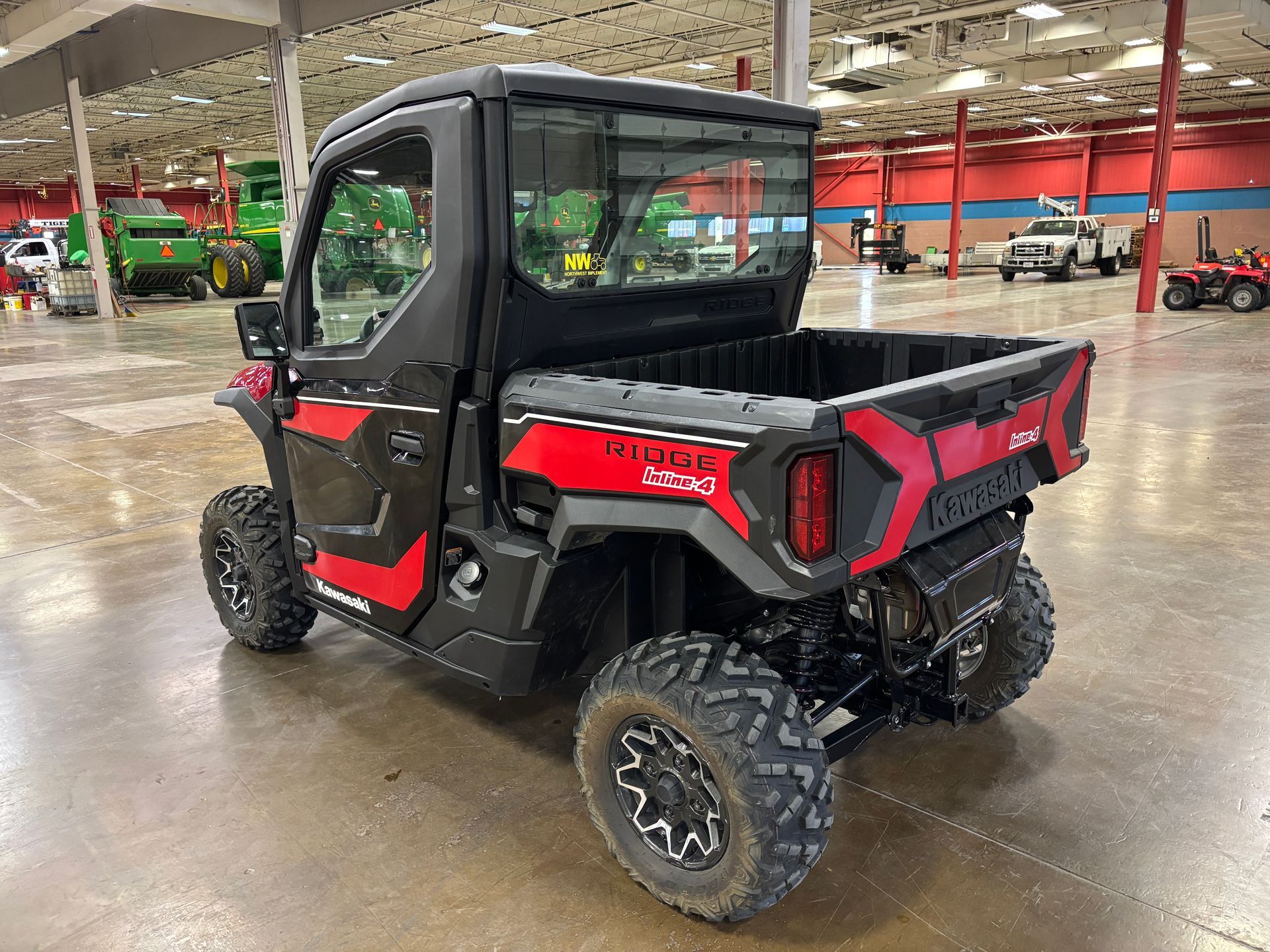 Black and red Kawasaki side-by-side utility vehicle in a showroom.
