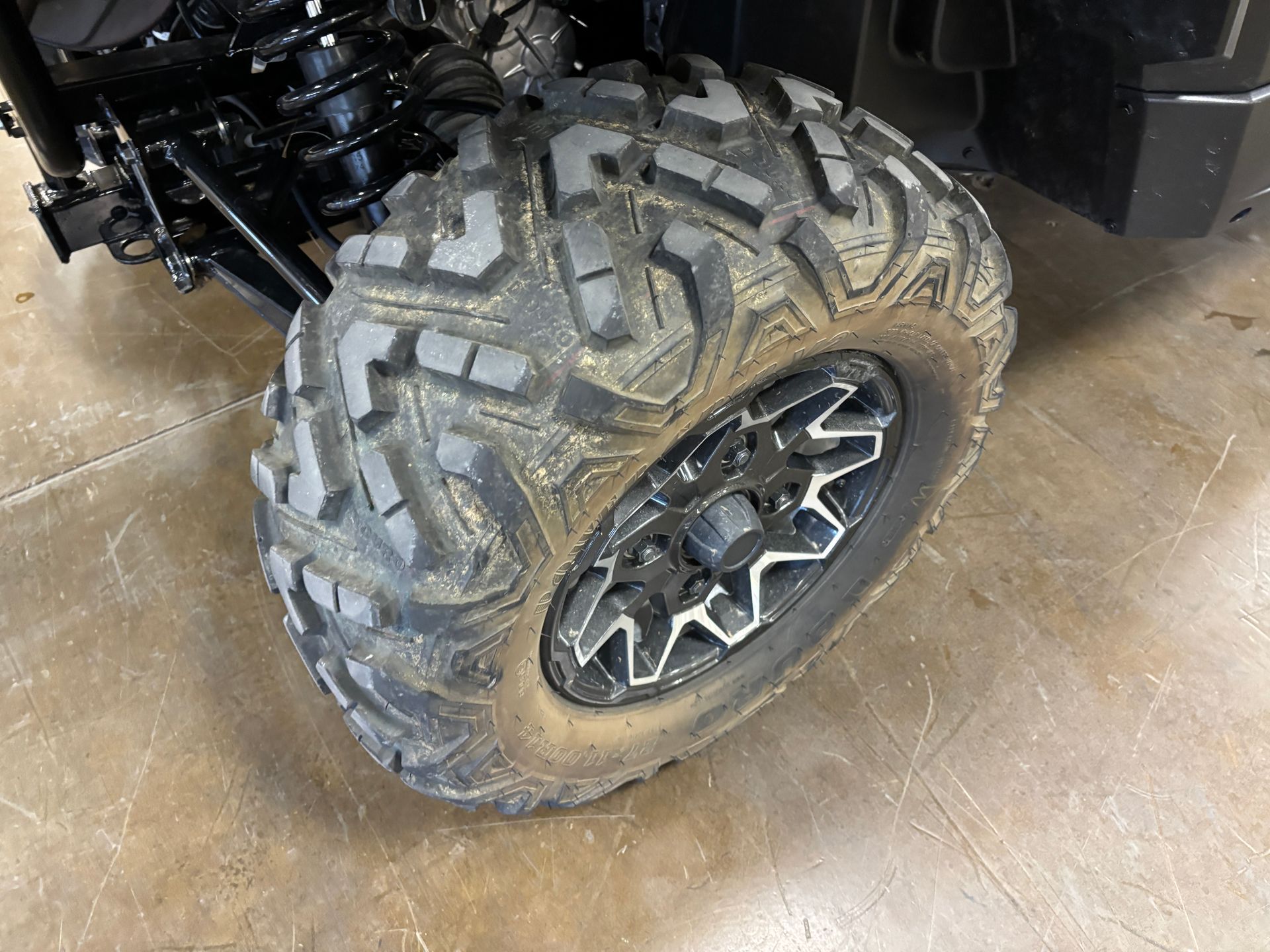 Black and silver ATV tire on a gray and black rim, with heavy tread.