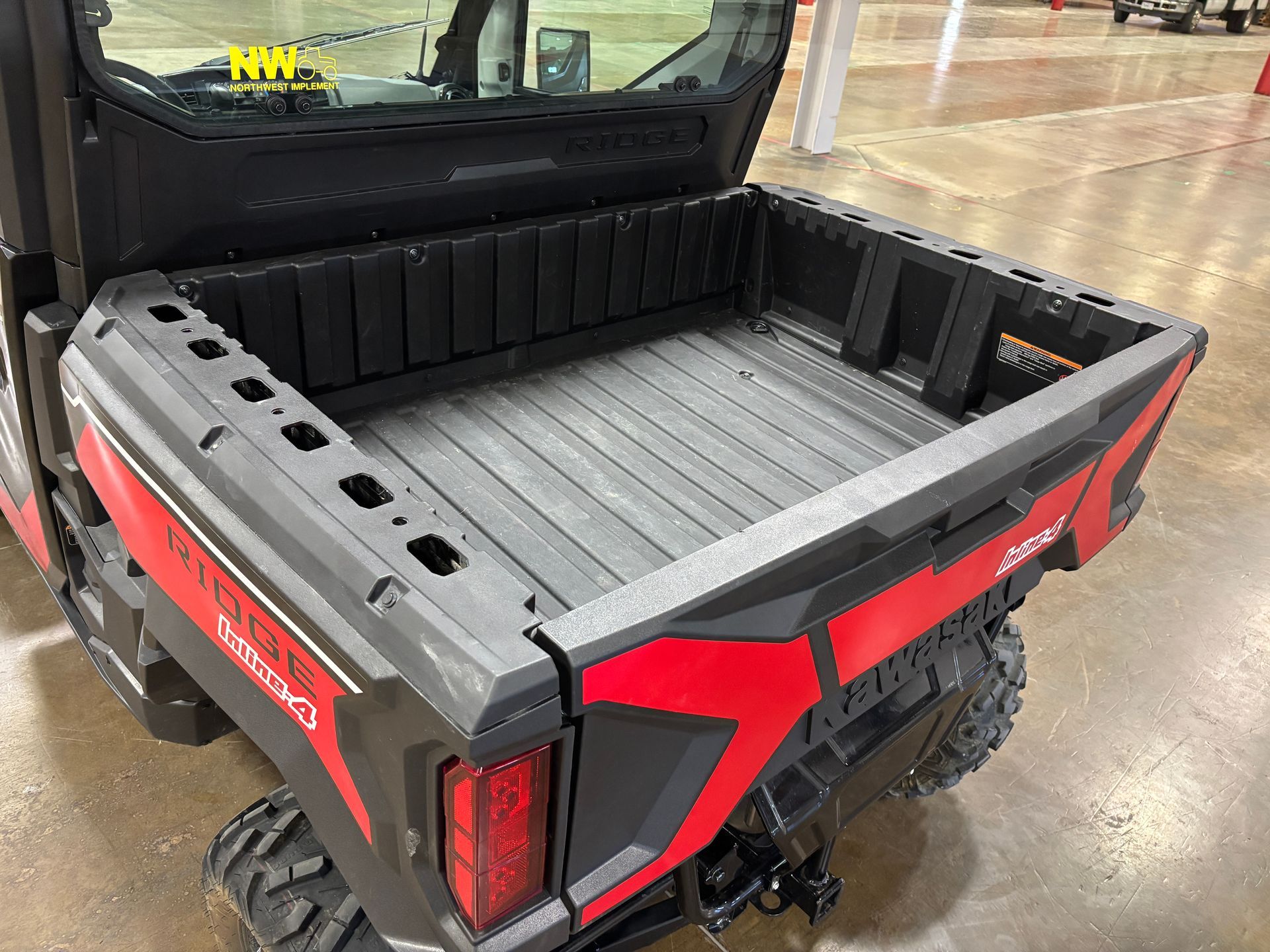 Black and red utility vehicle's open cargo bed; interior ribbed, exterior squared. Tail light visible.
