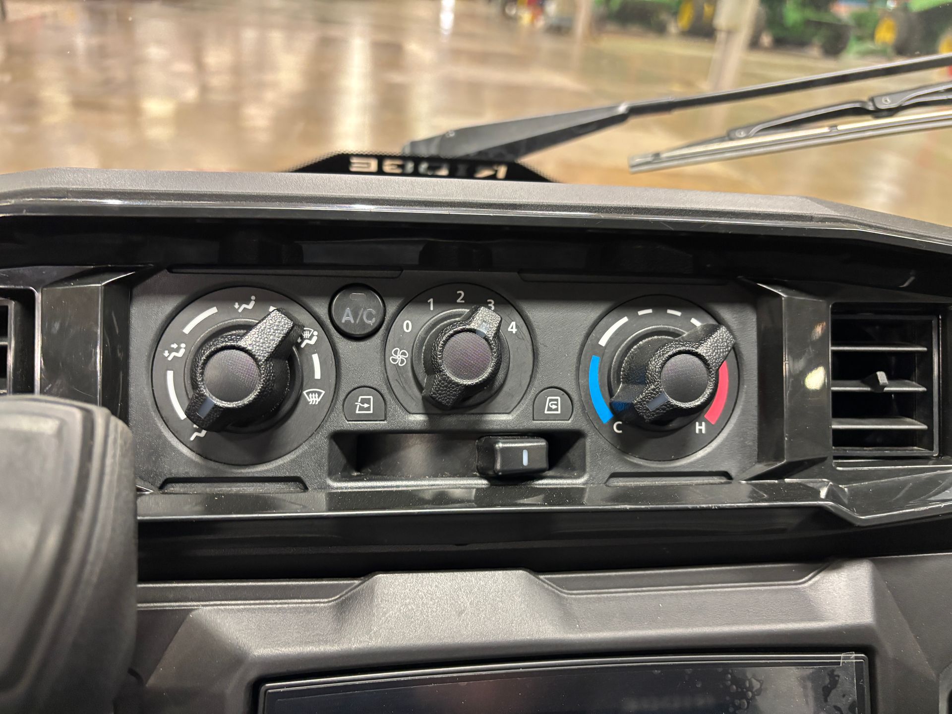 Dashboard with three black knobs for climate control. A/C button and air vents visible.