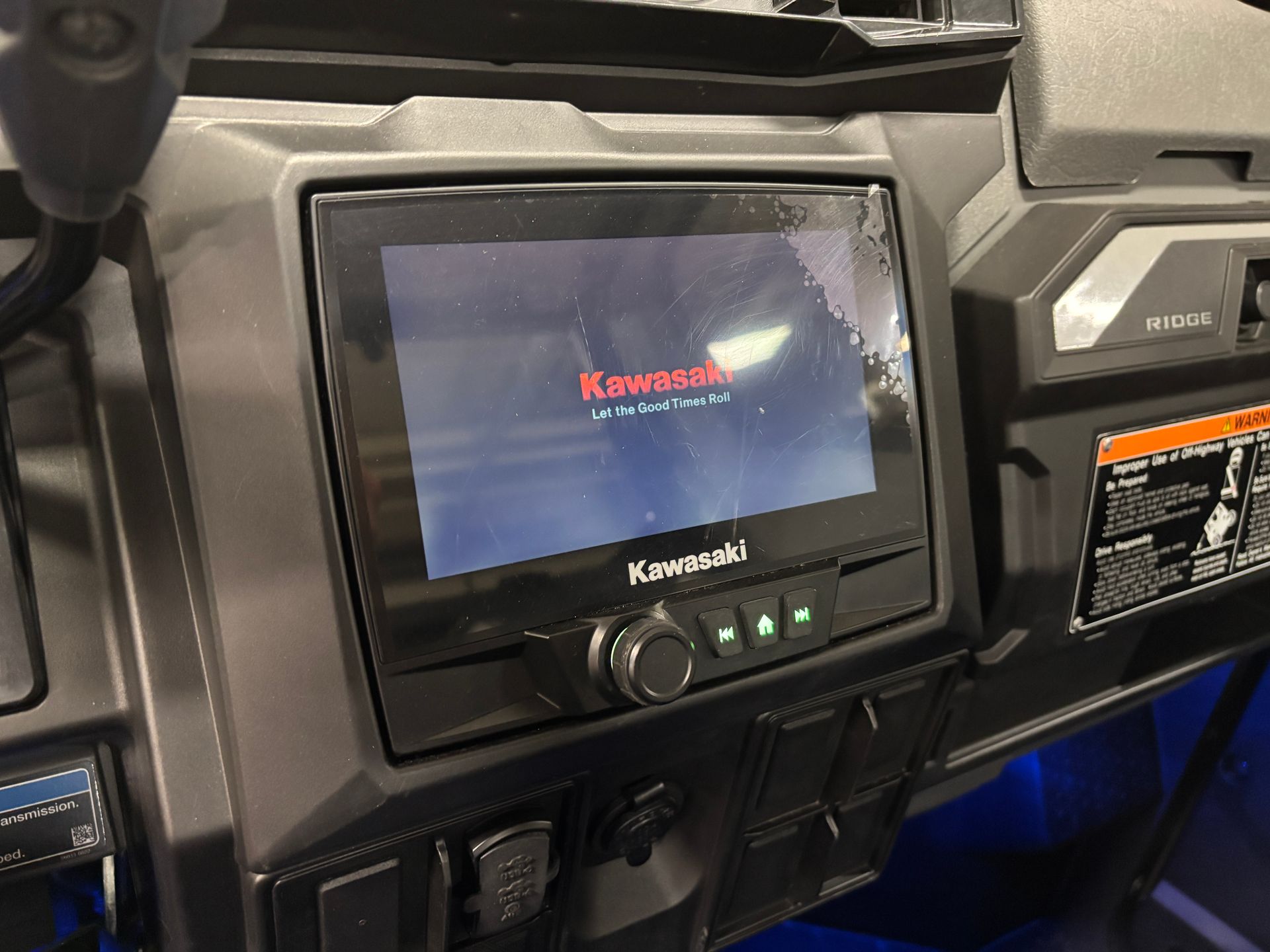 A Kawasaki UTV's dashboard with a screen displaying the Kawasaki logo.