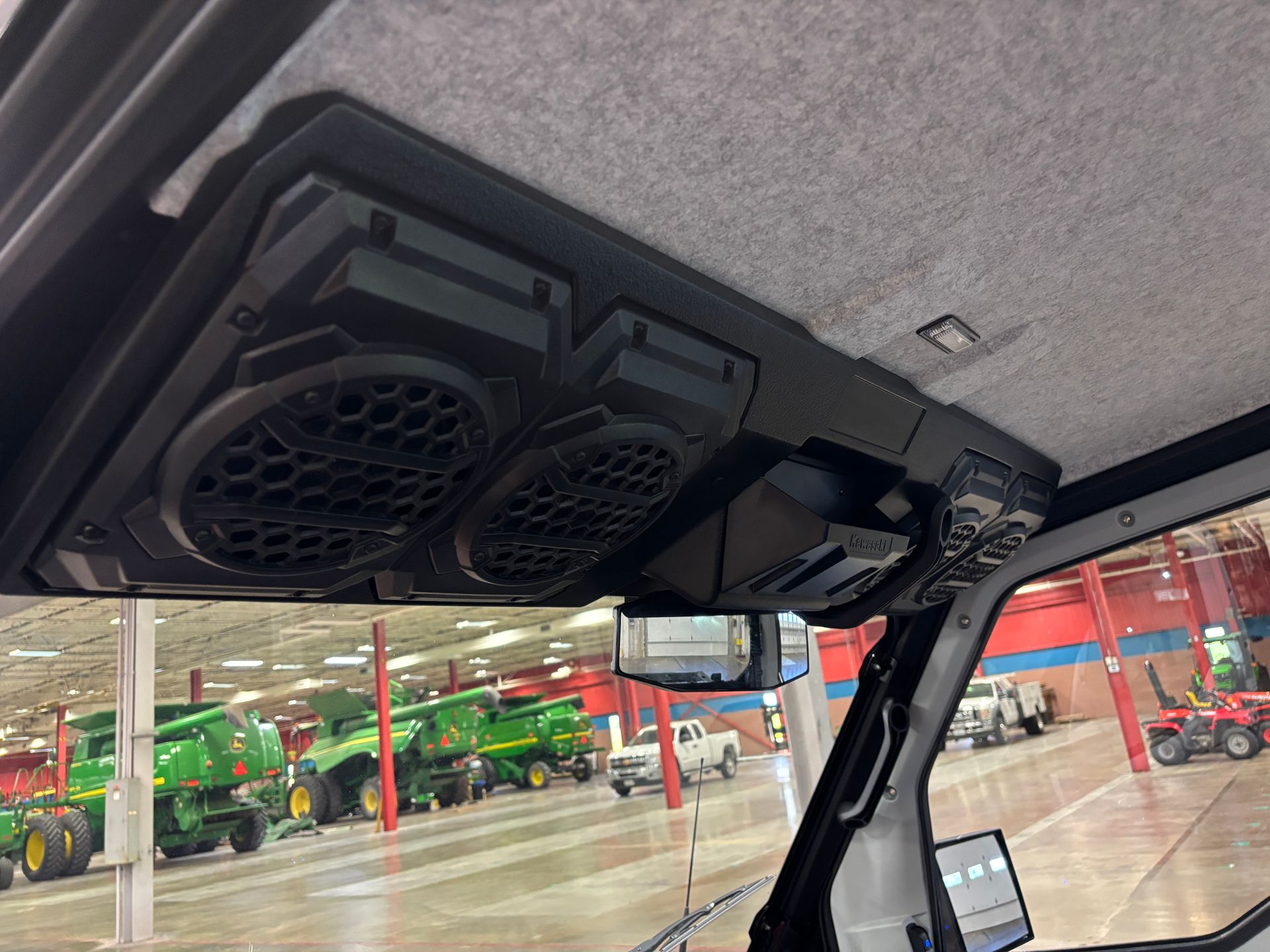 Interior of a vehicle roof with built-in speakers, a storage area, and a rearview mirror.