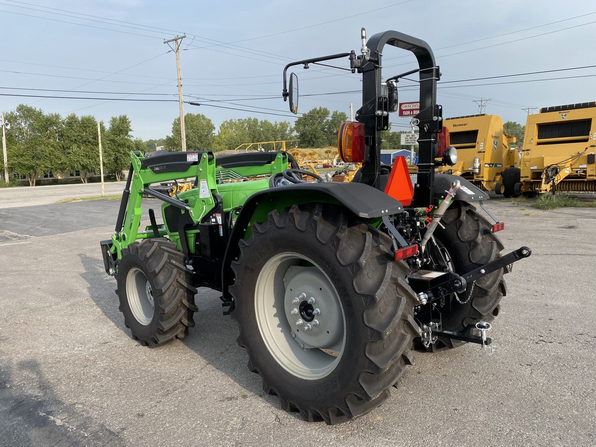 Green and black tractor with front loader parked outdoors.