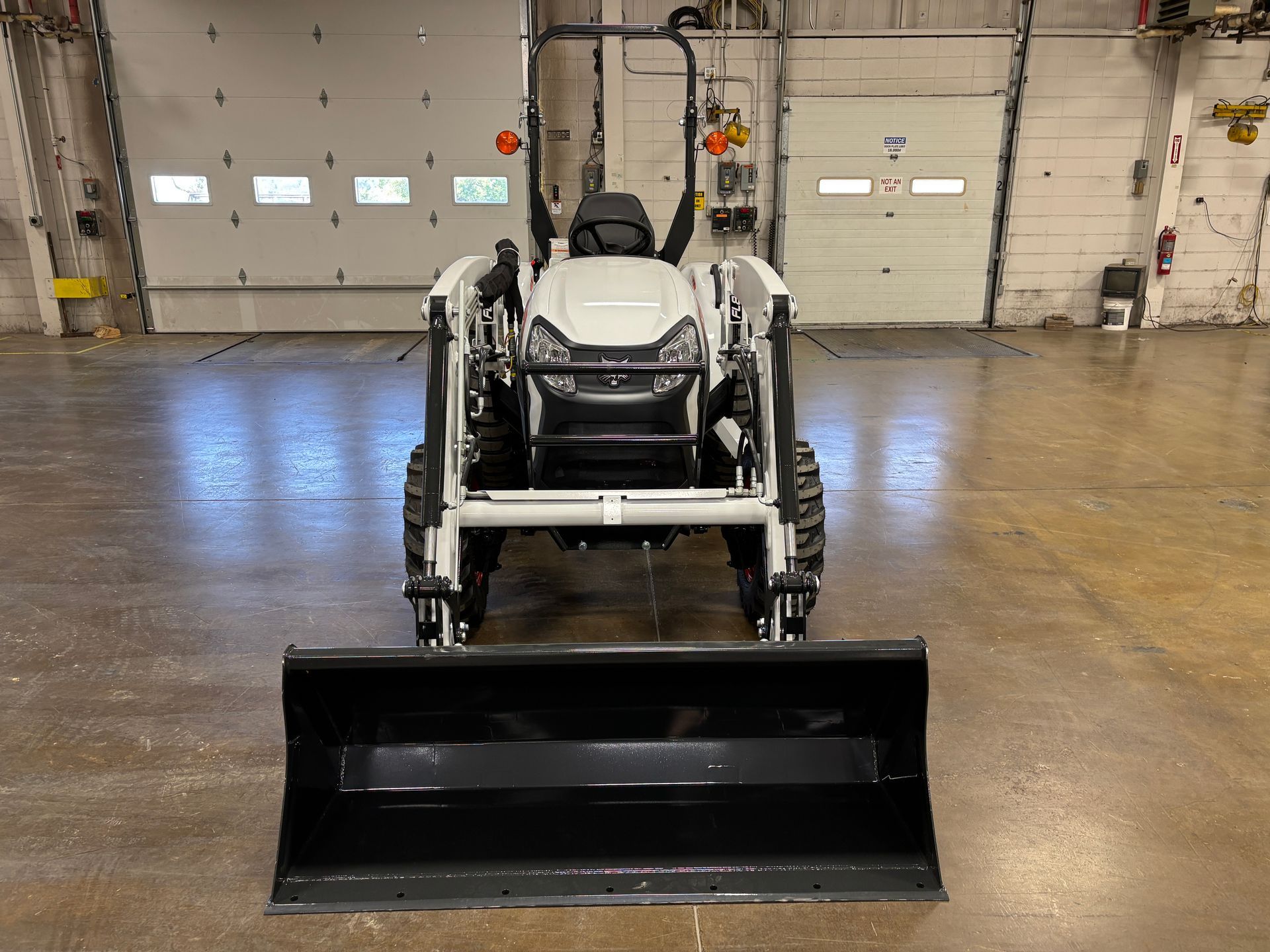 White tractor with a black front loader parked in a garage.