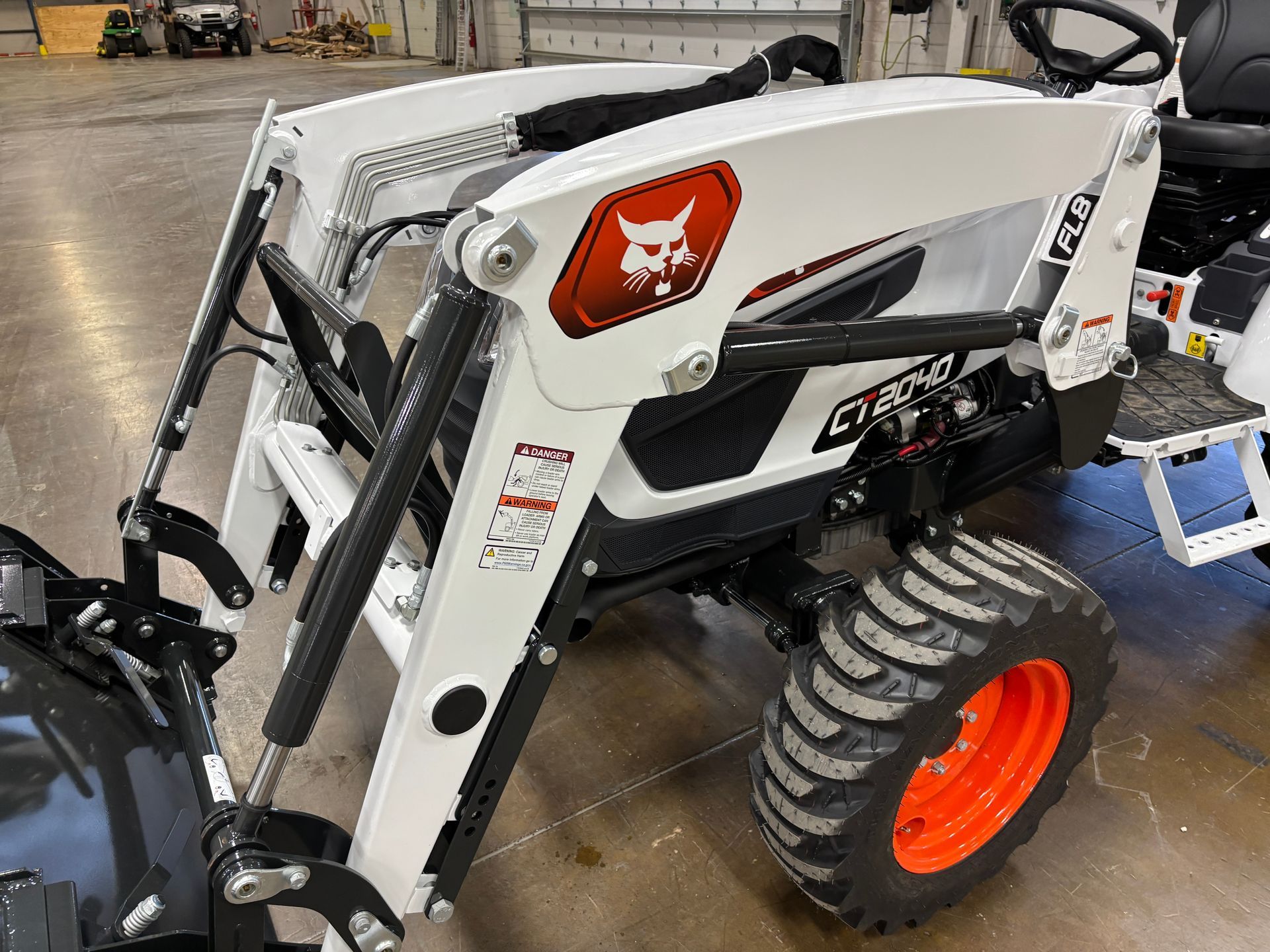 White Bobcat tractor with loader and orange accents, indoors.