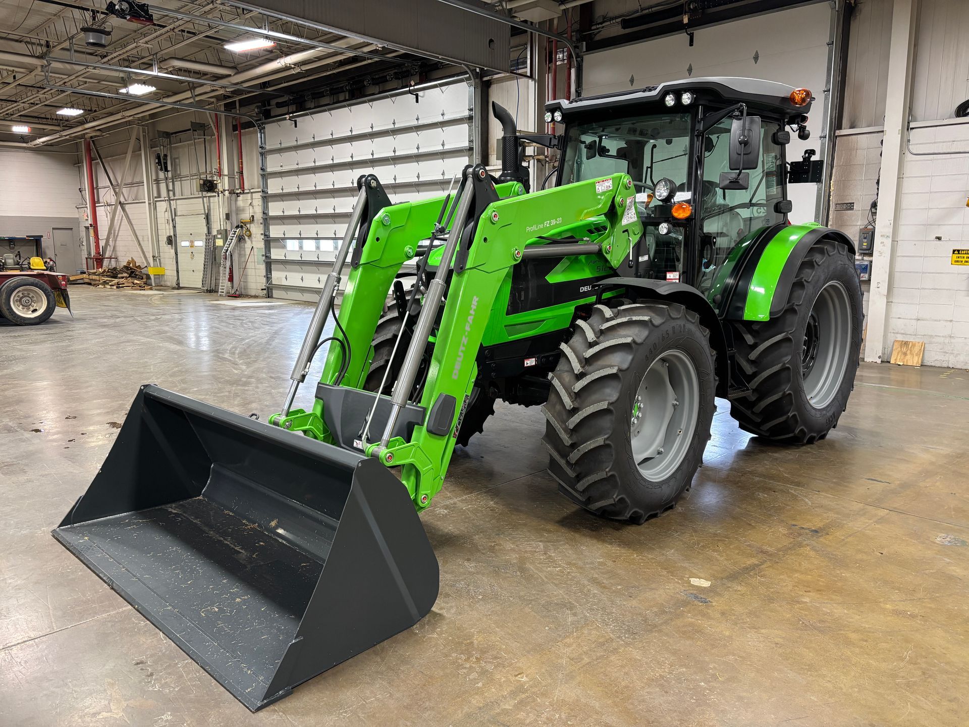 Green tractor with front loader inside a building.