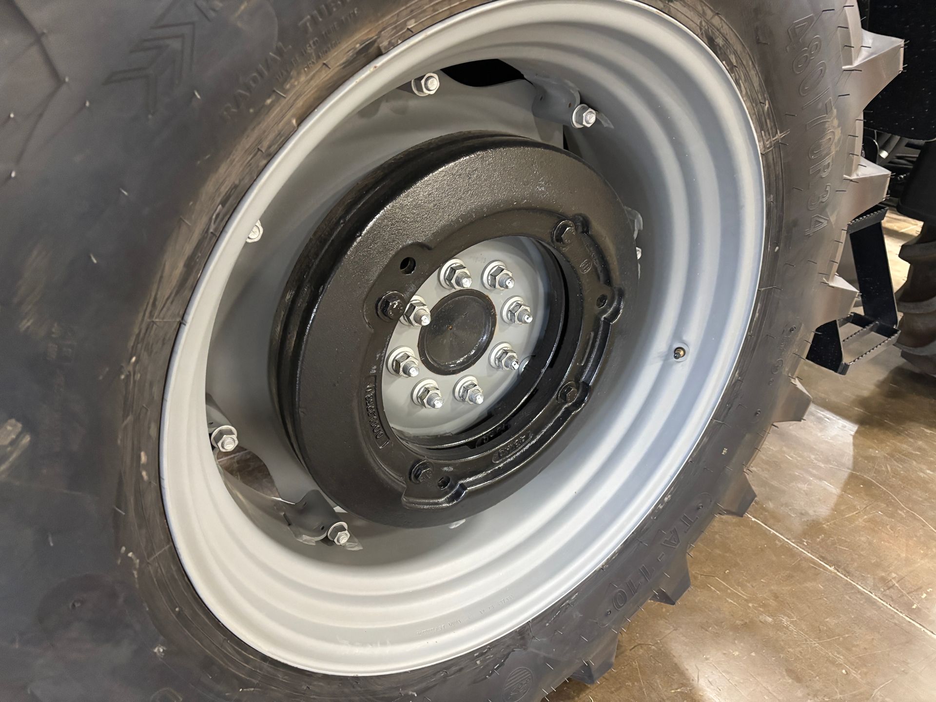 Close-up of a tractor wheel with a gray rim, tire, and a black brake assembly.