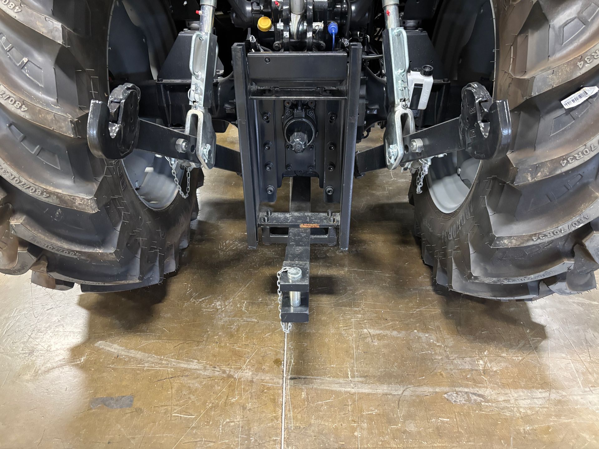 Rear view of a tractor with large tires, hitch, and various mechanical components.