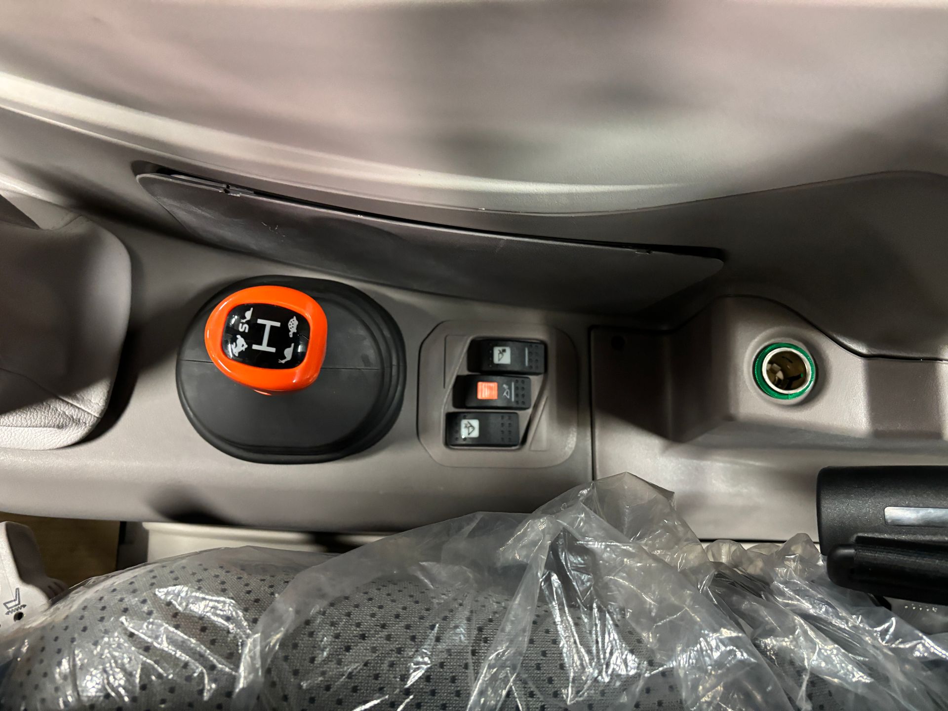 Dashboard with orange lever and black buttons, inside a vehicle.