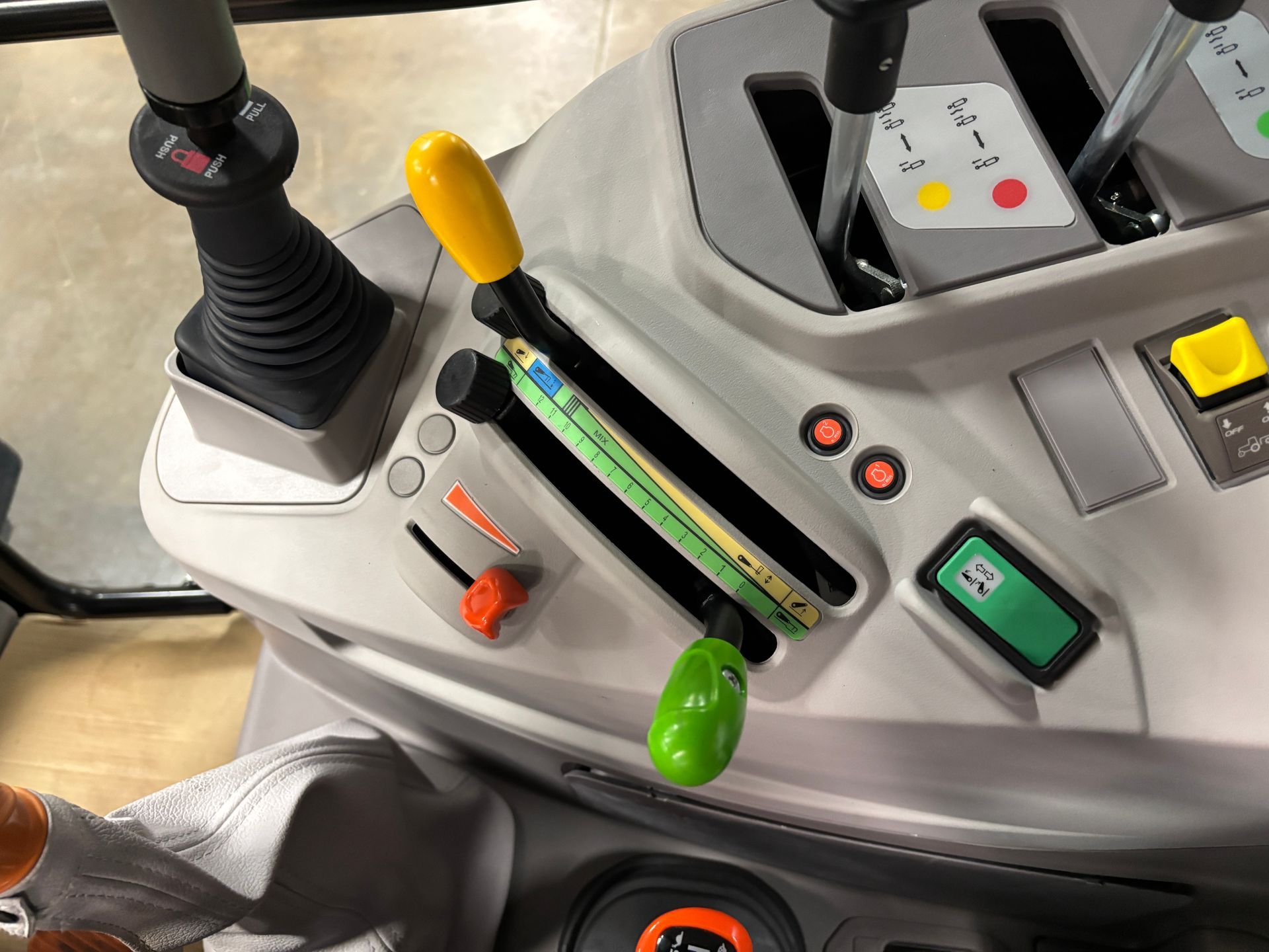 Tractor control panel with levers and buttons in gray and black with yellow, green, and orange accents.