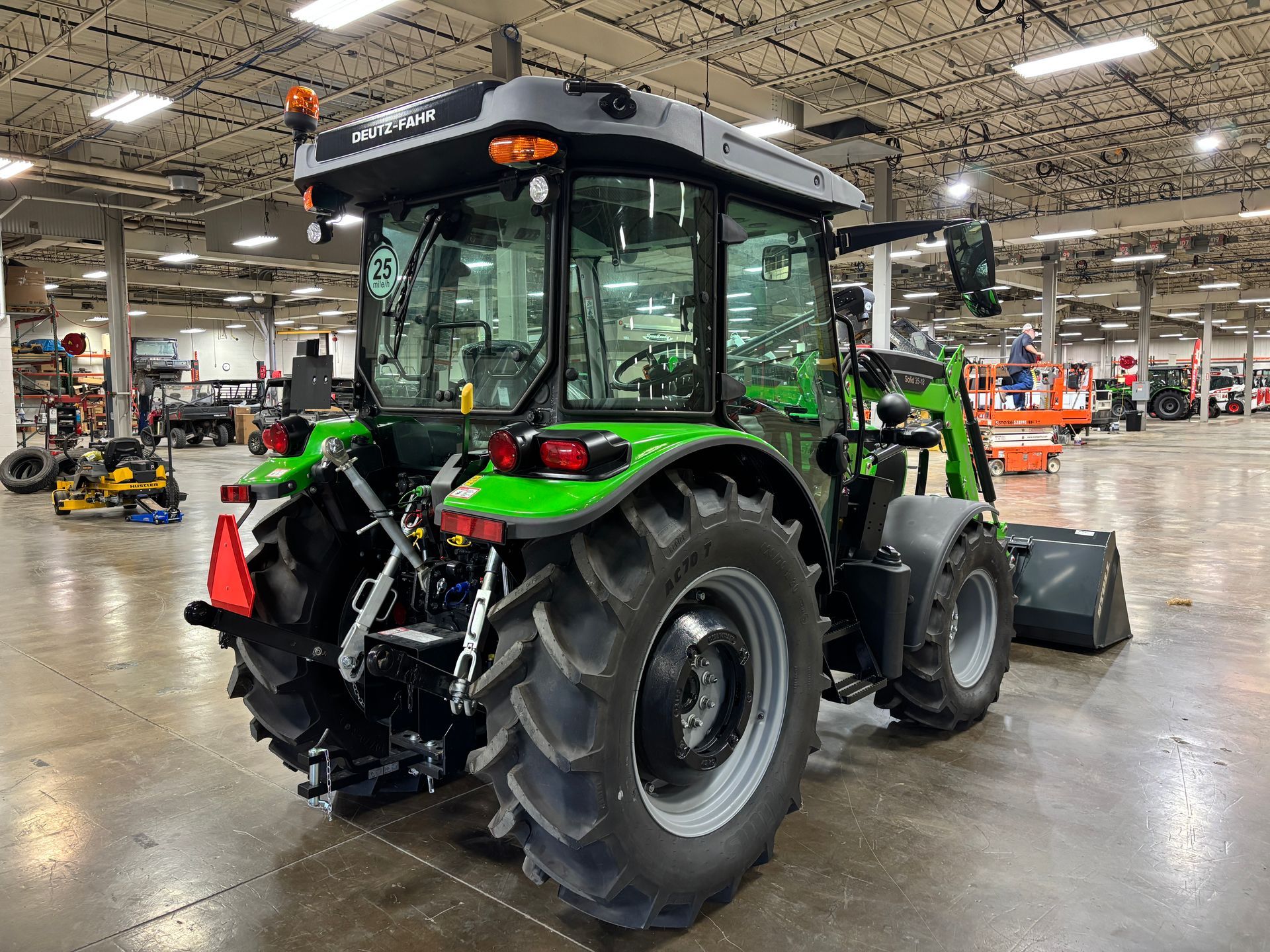 Green tractor with black and gray accents, parked inside a warehouse.