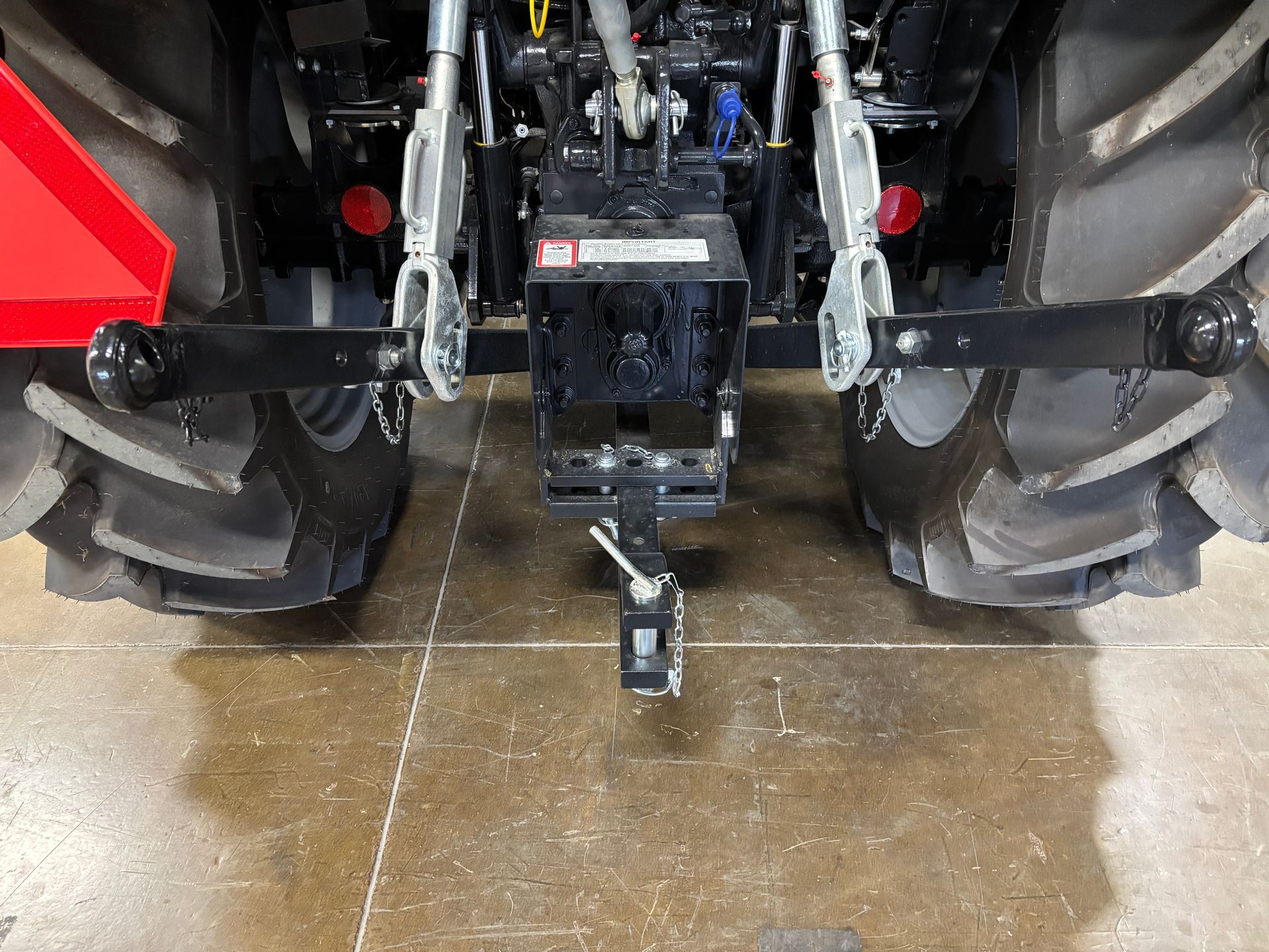 Rear view of a tractor with black hitch and adjustable arms, two large tires visible.
