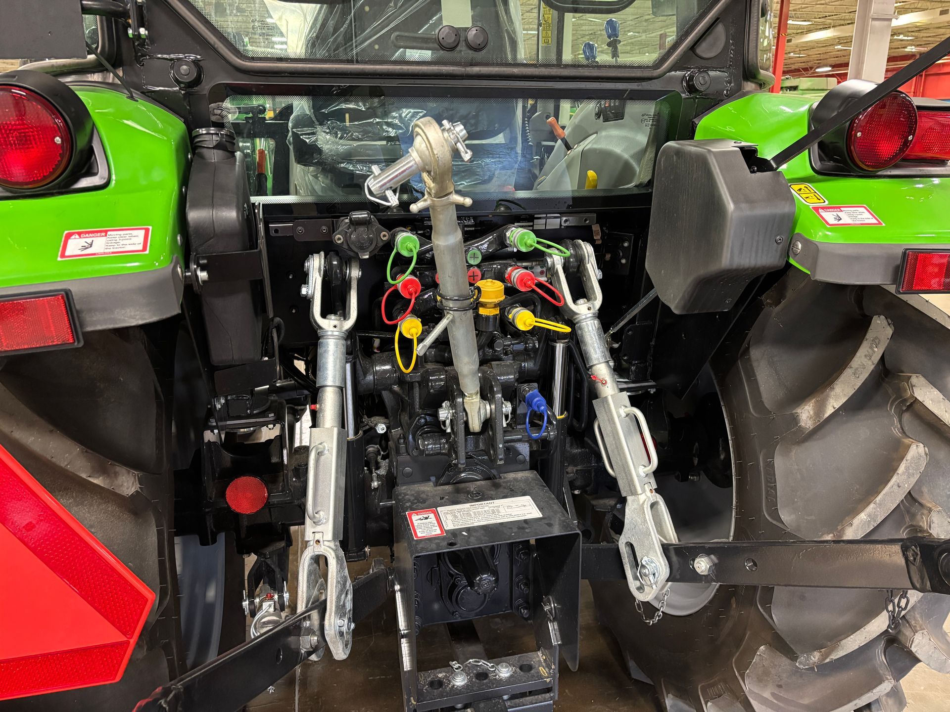 Rear view of a green and black tractor with three-point hitch and hydraulic connections.