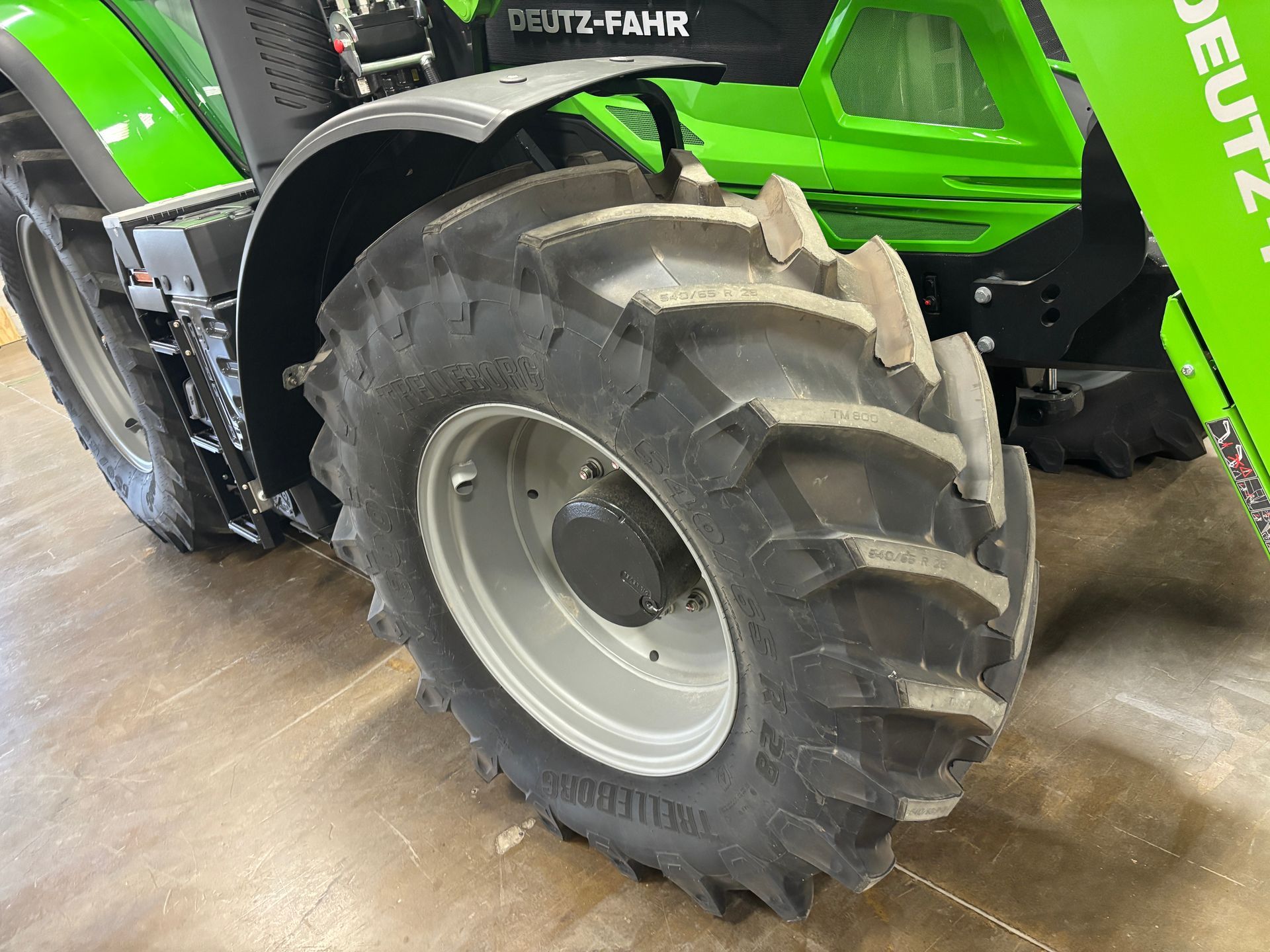 Close-up of a green and black Deutz-Fahr tractor's large rear tire, with mud and tread visible.