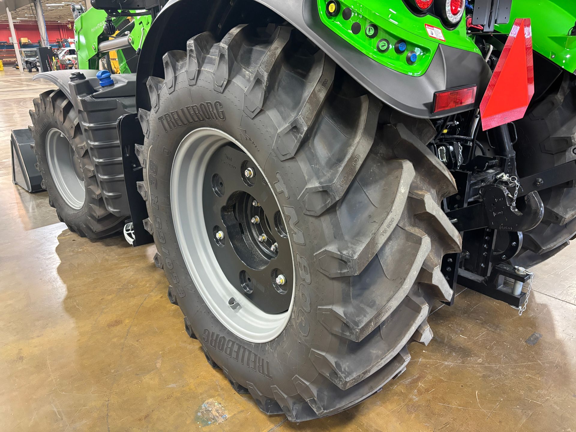 Rear tire and wheel of a green and black tractor.