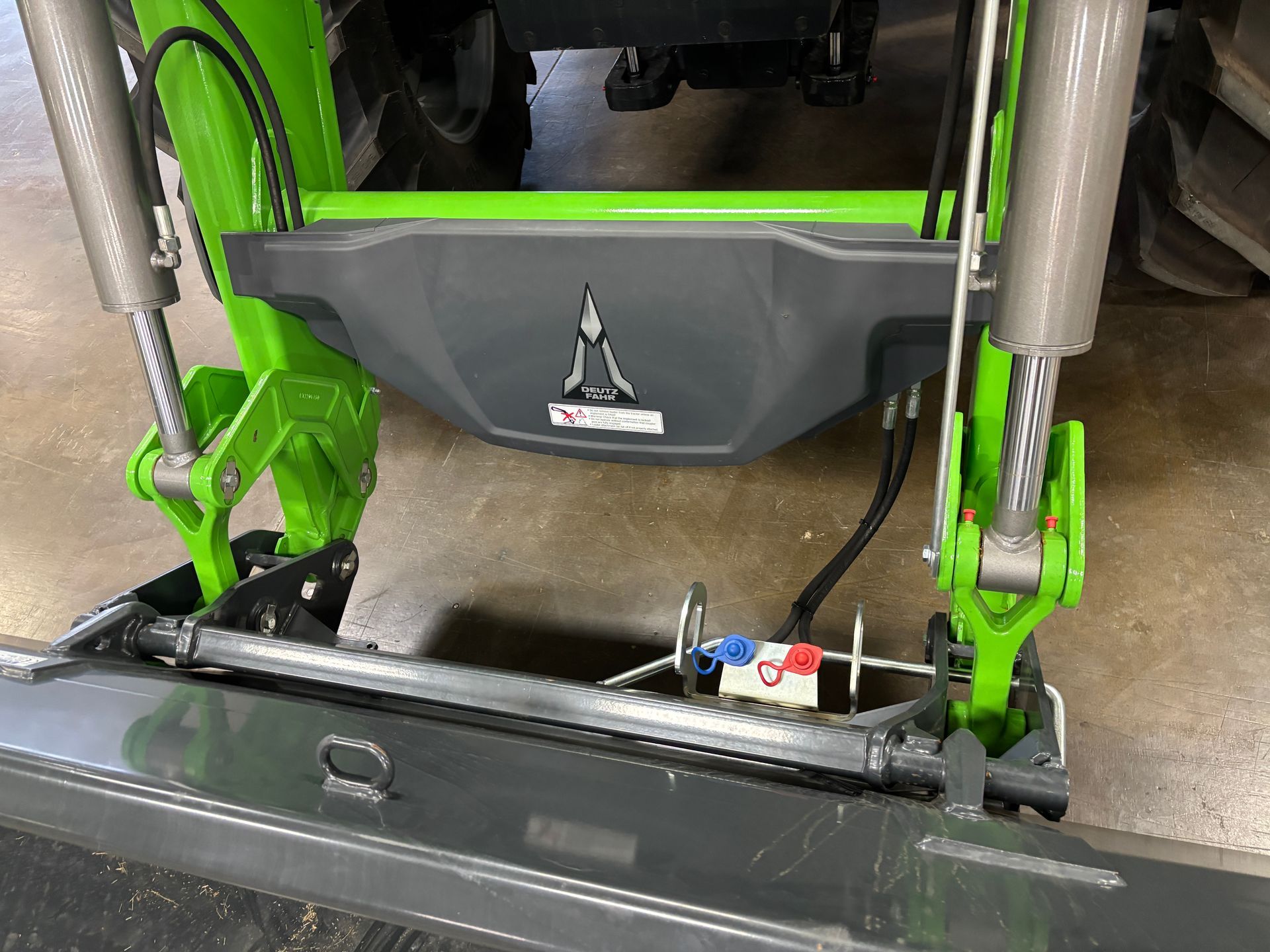 Close-up of a green and gray farm machine with a central compartment and support arms.