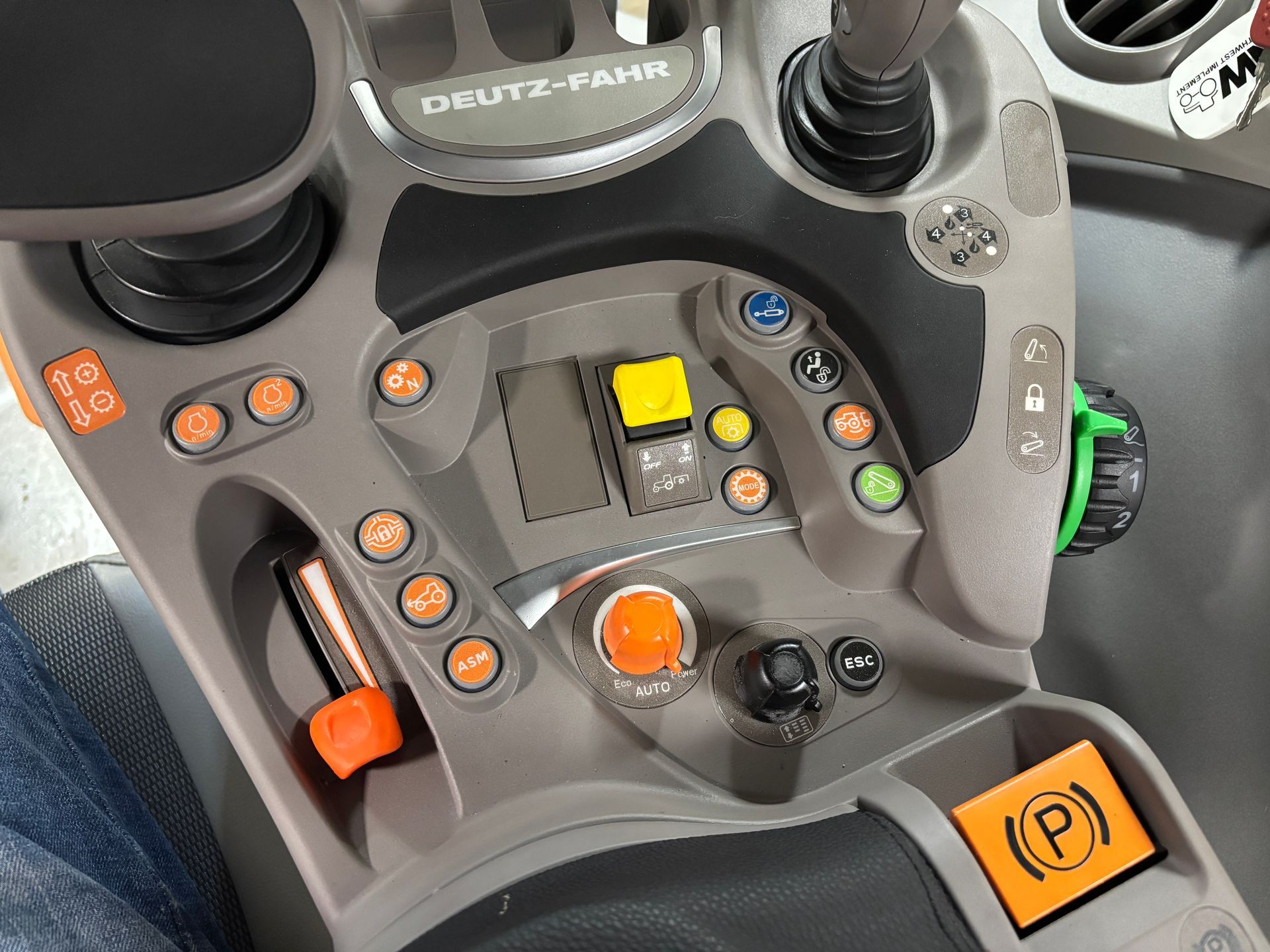 Close-up of a Deutz-Fahr tractor console with orange and yellow buttons and levers.