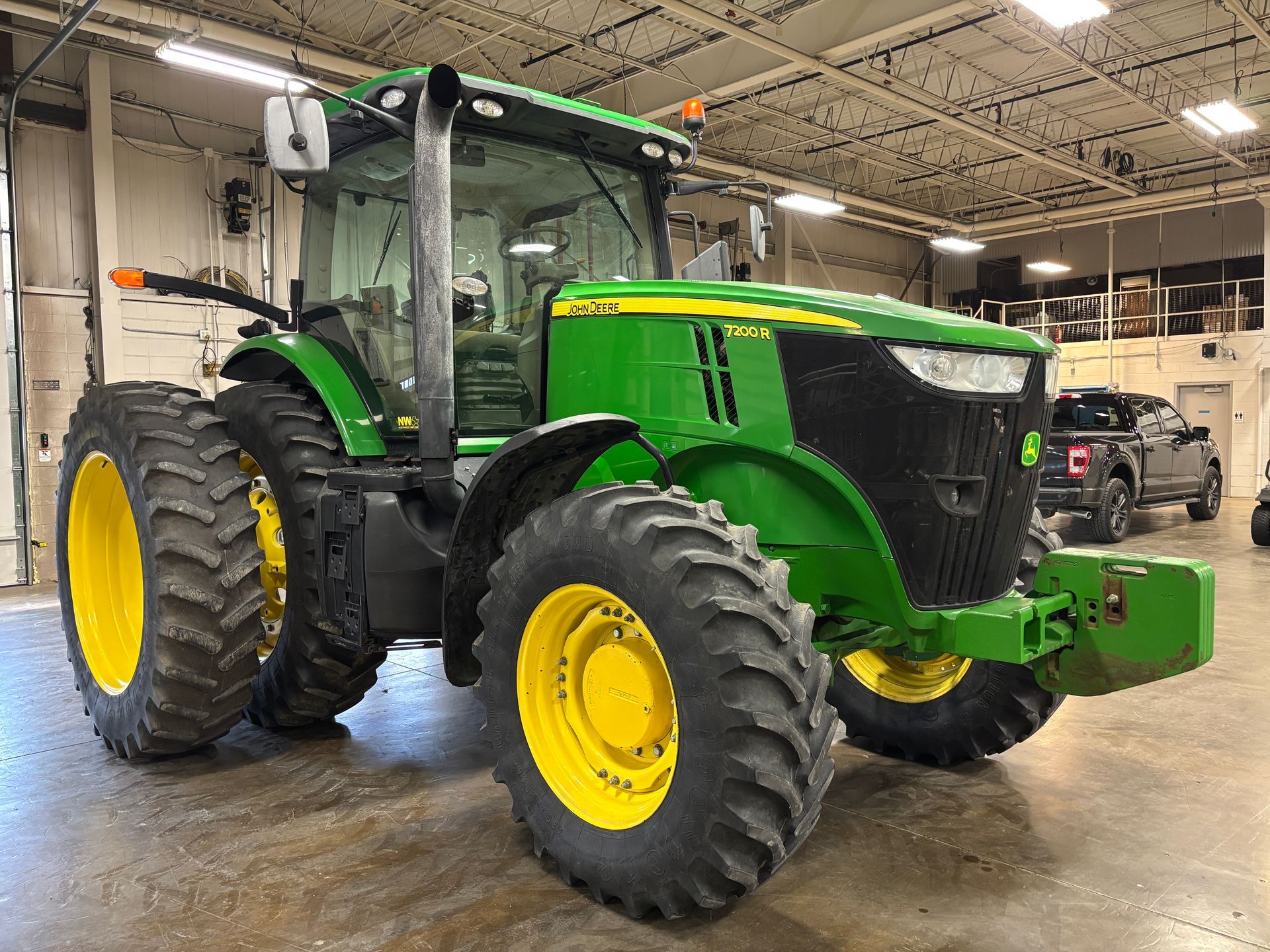Green and yellow John Deere tractor in a building with a gray floor.