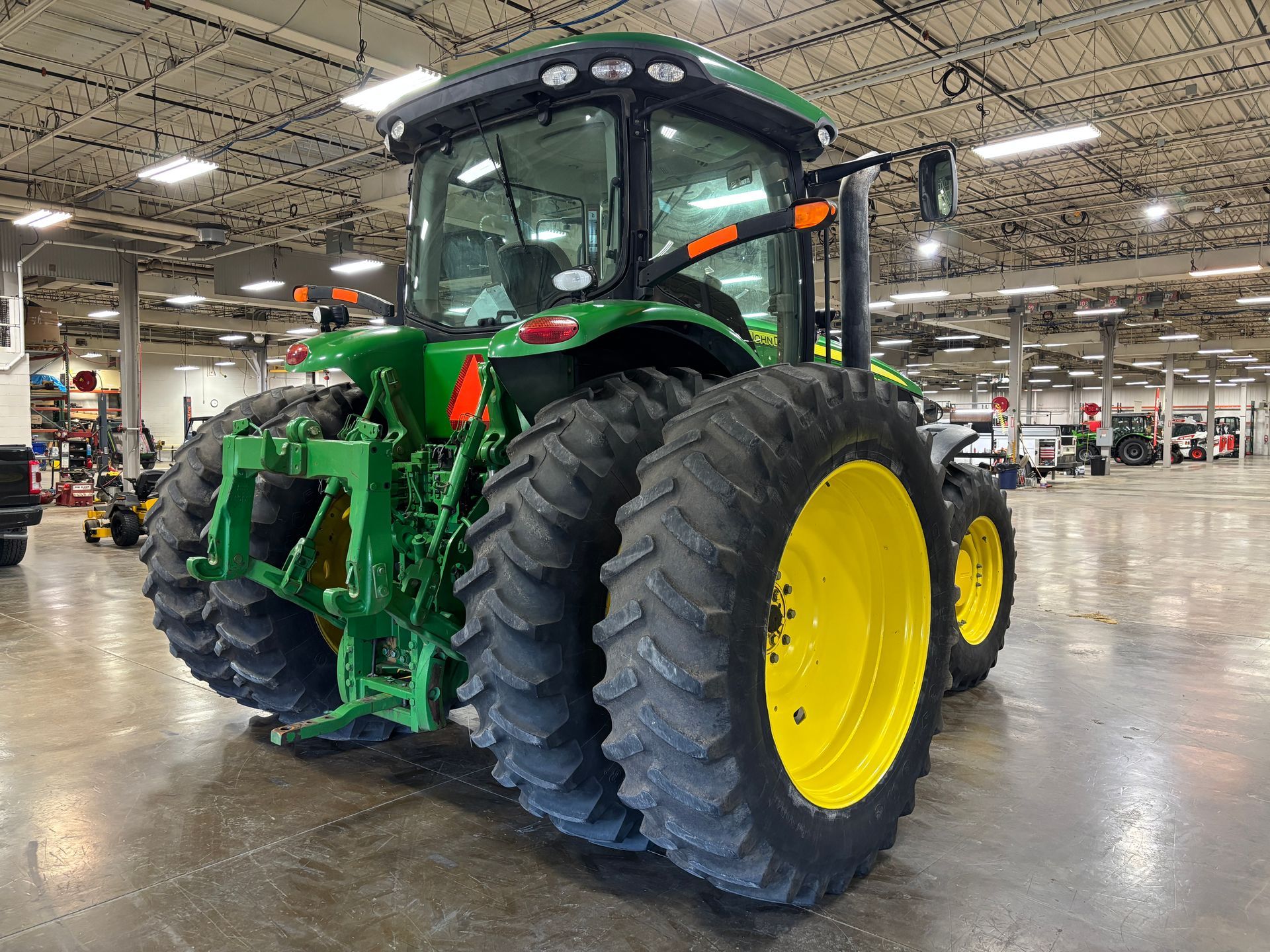 Green and yellow John Deere tractor, rear view, in a large warehouse.