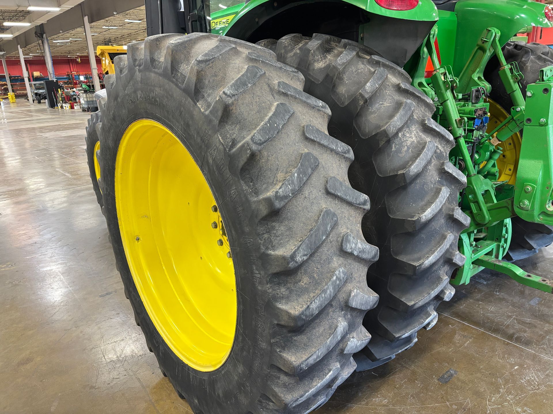 Close-up of a John Deere tractor's rear tires and yellow wheel.