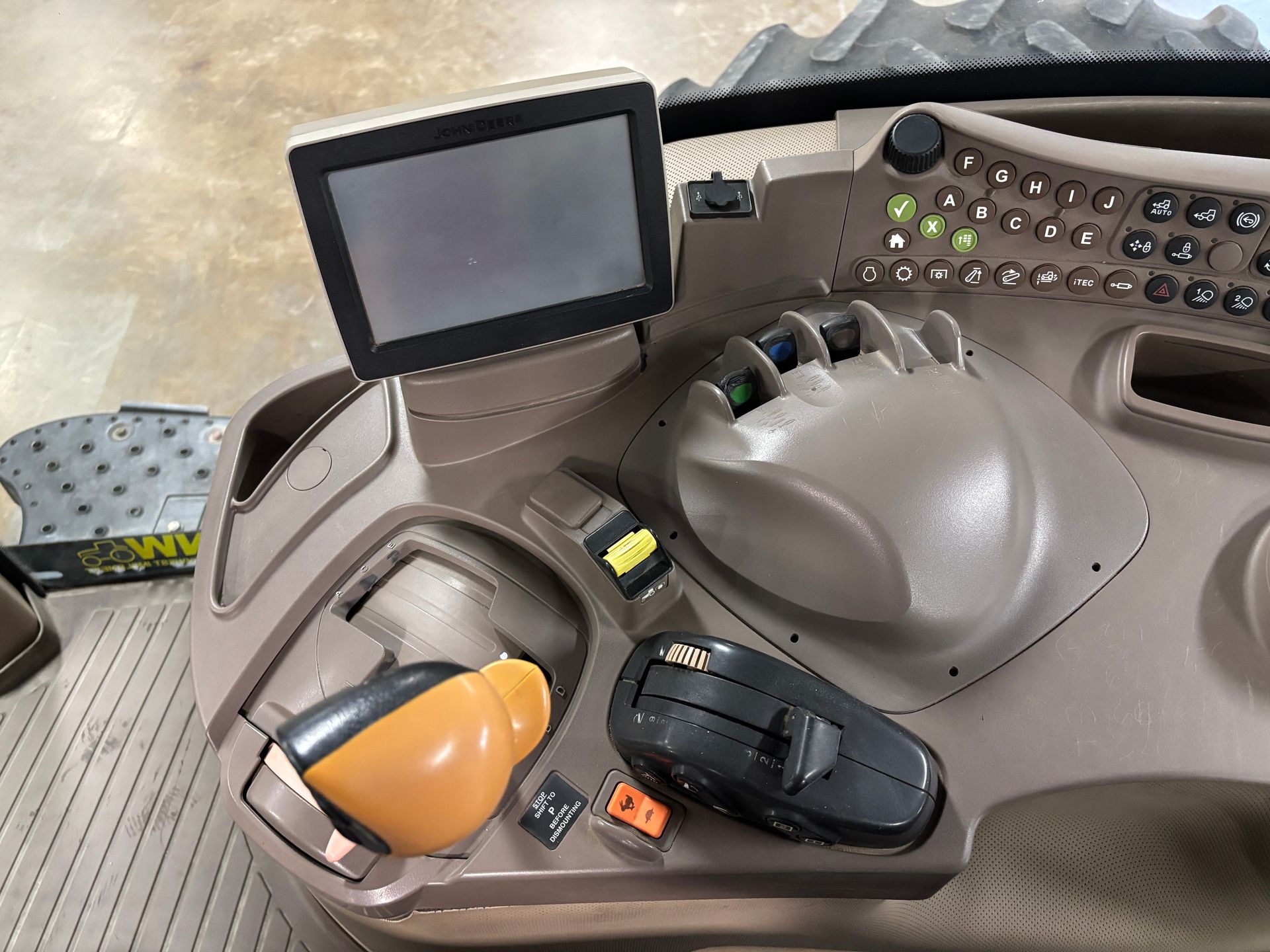 Dashboard console of agricultural machinery. Beige with a screen, control levers, and buttons.