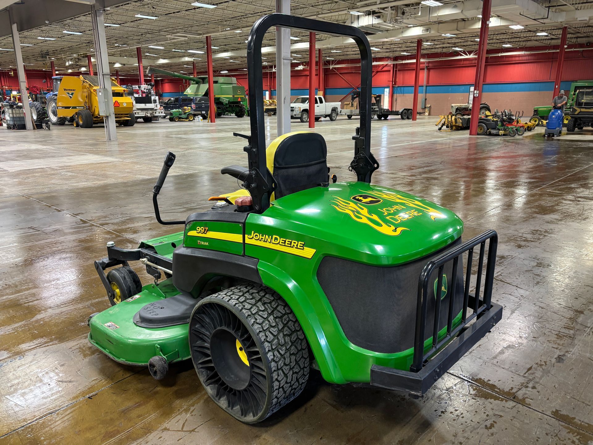 Green John Deere riding lawn mower with black roll bar and unique tires.
