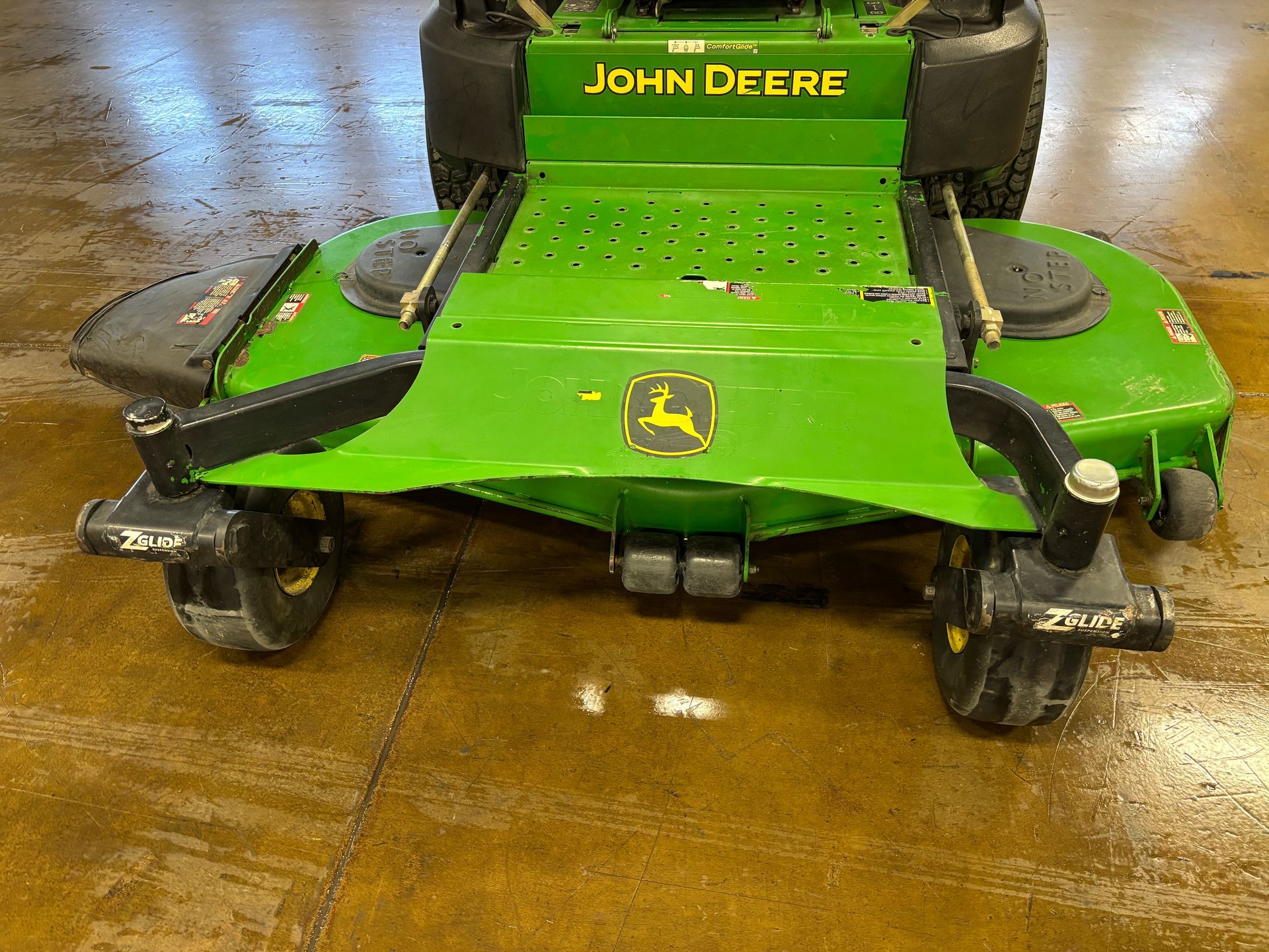 Green John Deere zero-turn lawnmower on a smooth surface.