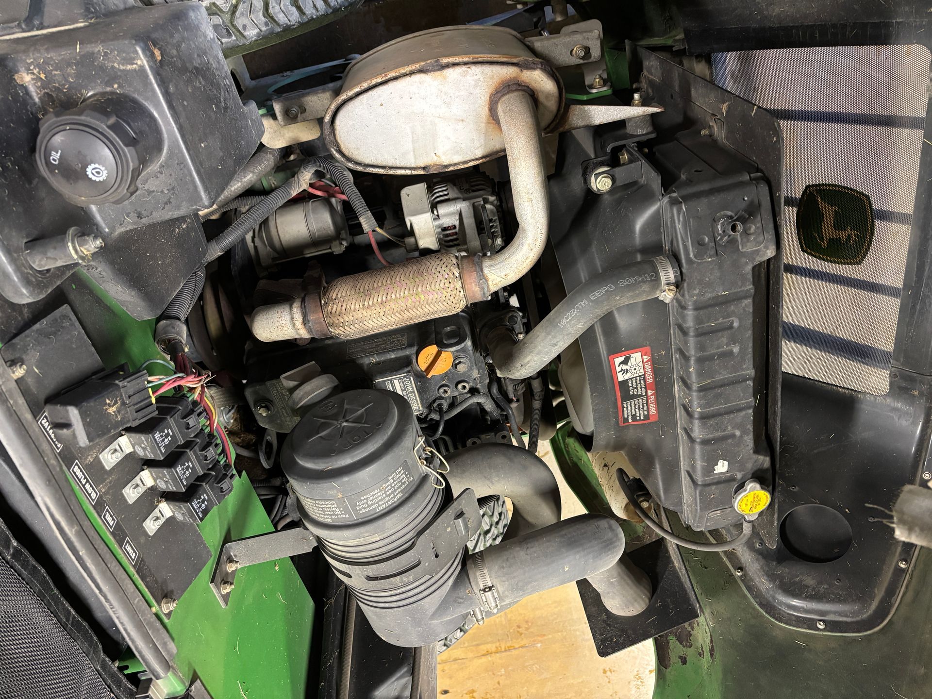 Engine of a John Deere vehicle with various components visible, including exhaust, air filter, and radiator.