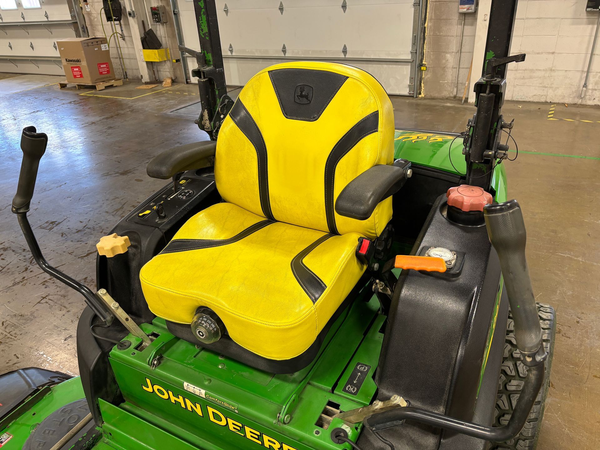 John Deere riding lawn mower with yellow and black seat; green body.
