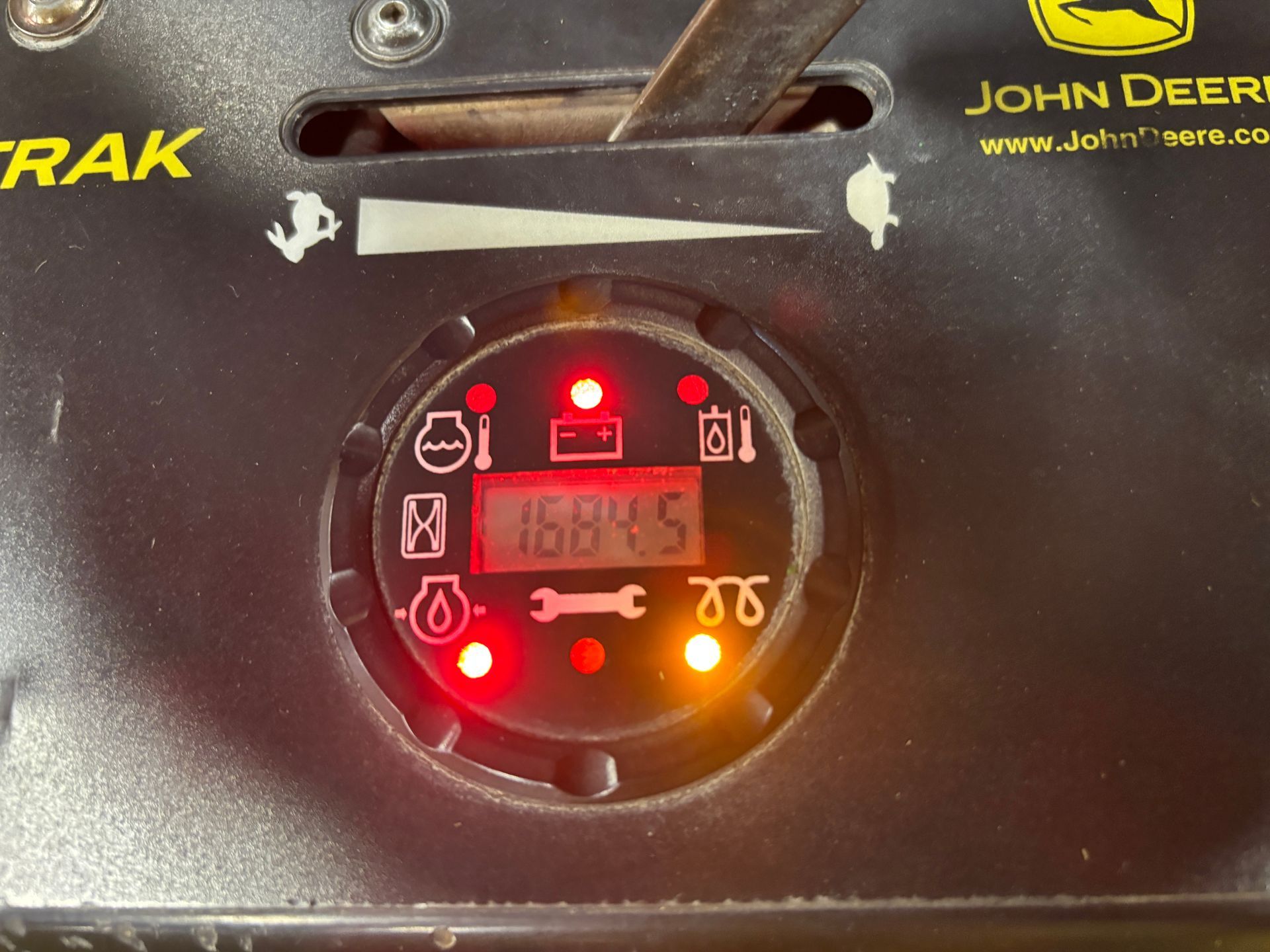 Dashboard of a John Deere lawnmower with multiple red warning lights illuminated and a digital display showing 16845.